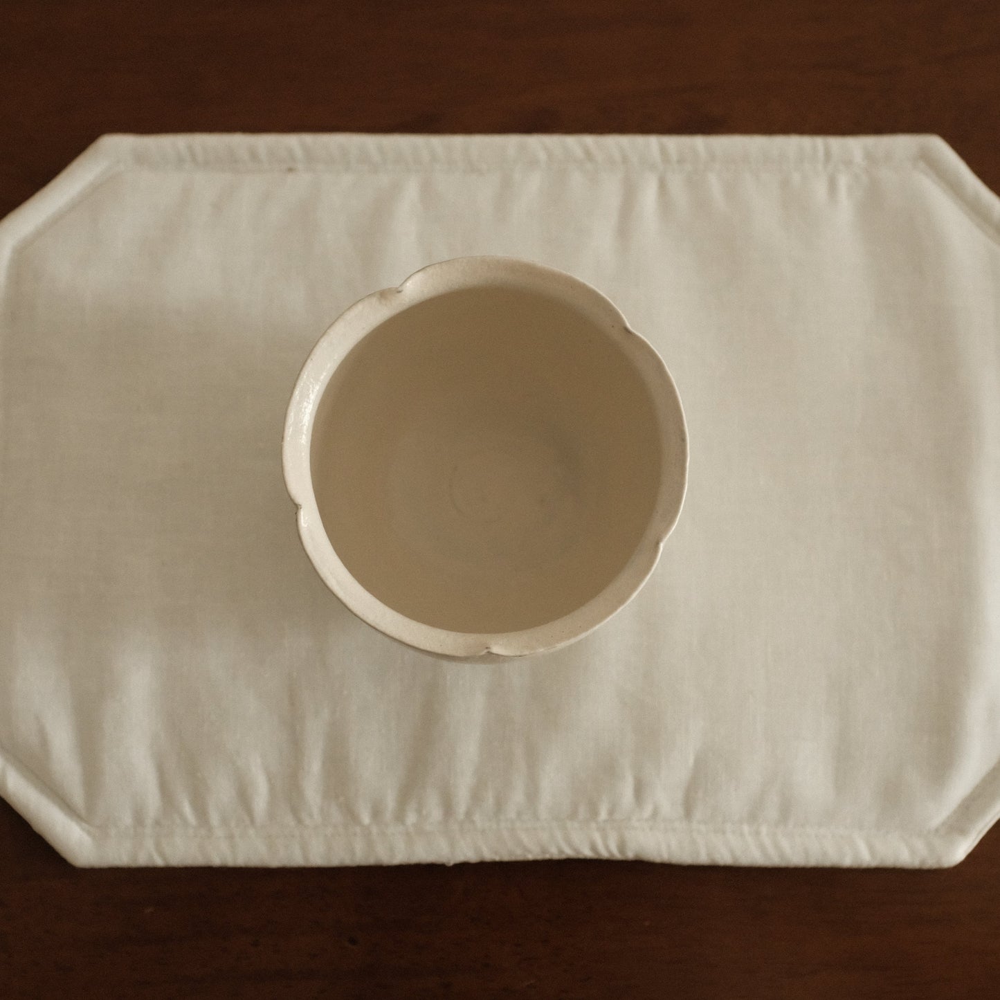 White ceramic floral rim cup on a textured white surface with a brown