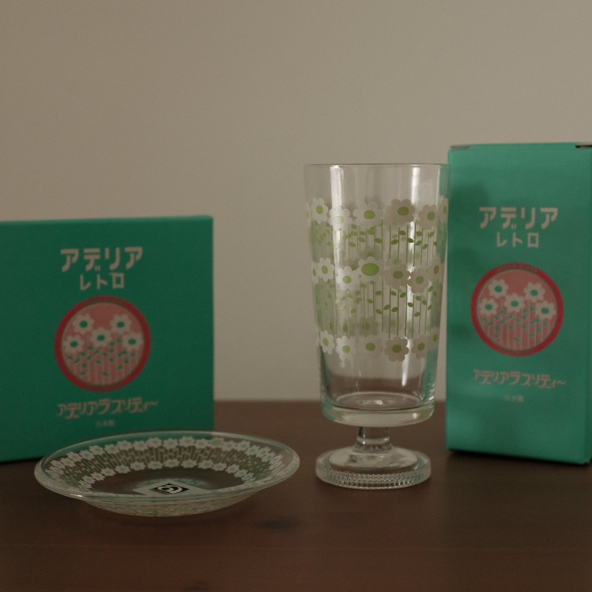 Green packaging with a red logo and a clear glass on a wooden surface.