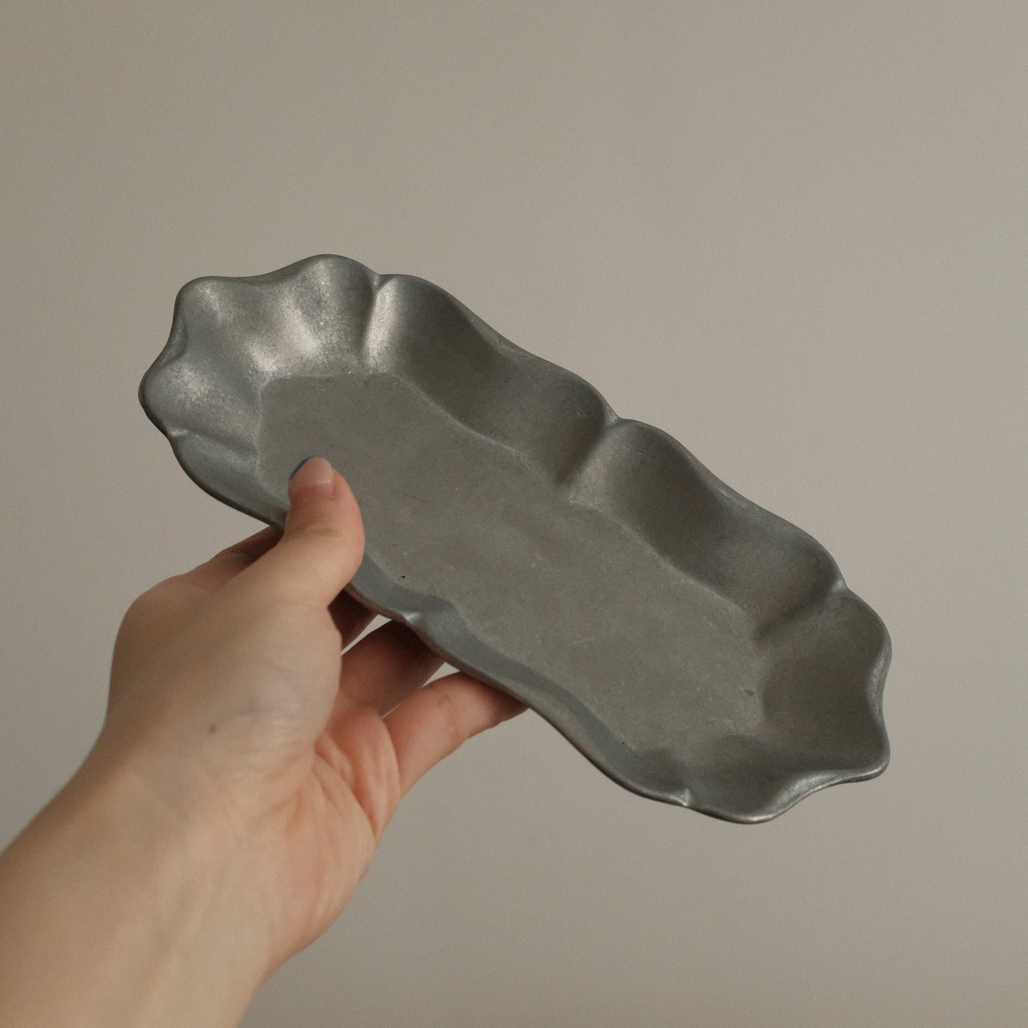 Hand holding a gray ceramic dish against a plain background