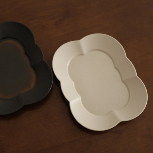 Two ceramic plates, one black and one white, on a wooden surface.