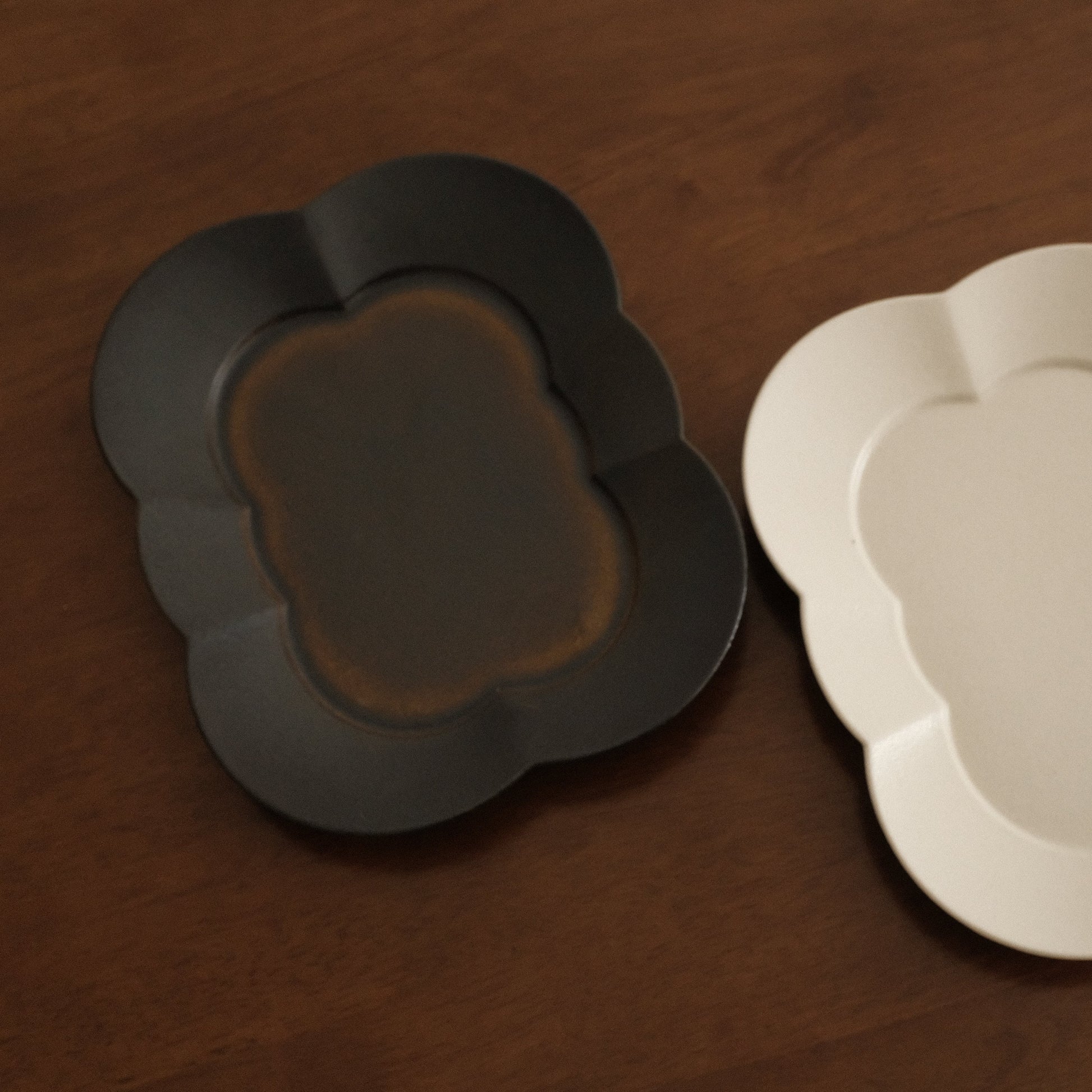 Two ceramic plates, one black and one beige, on a wooden surface.