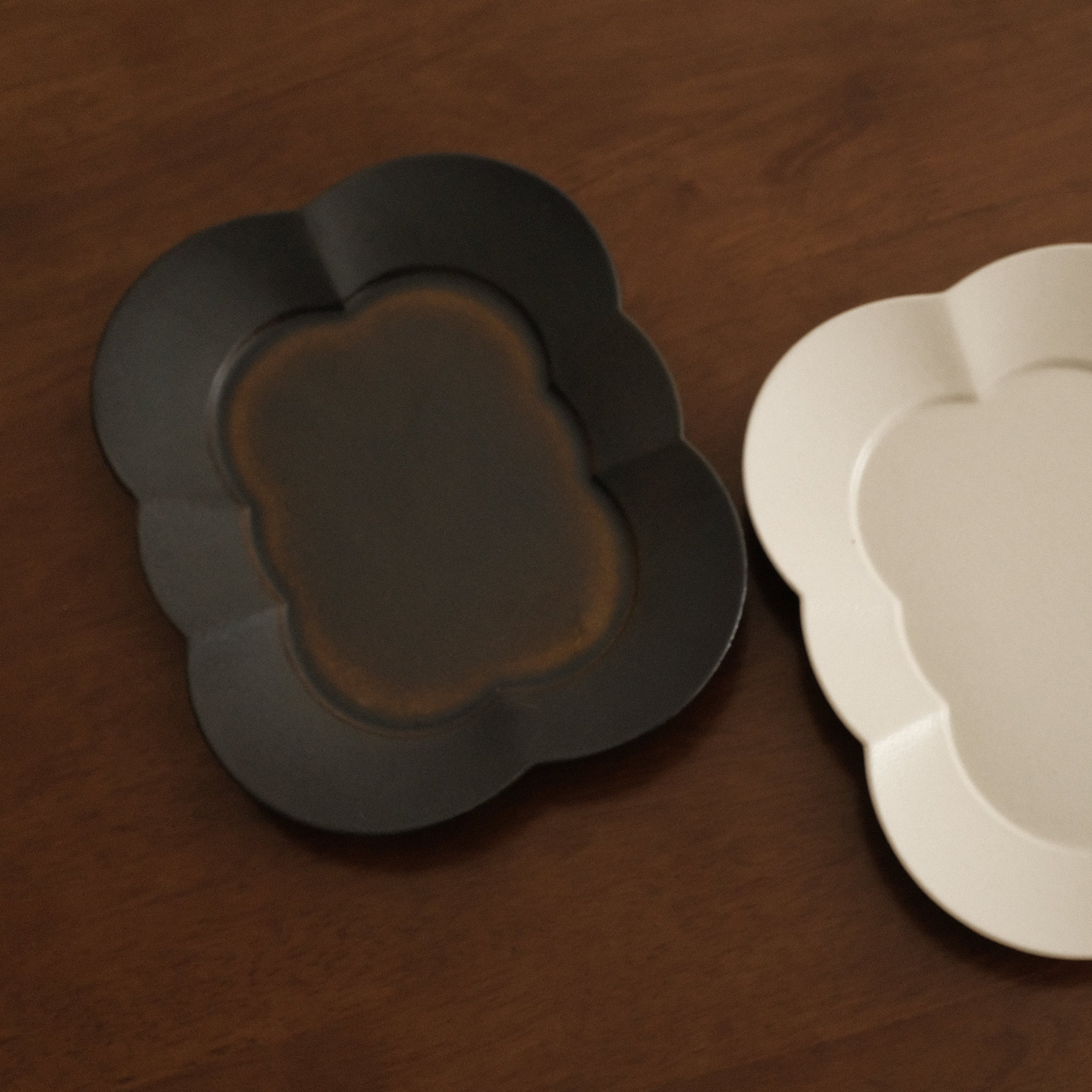 Two ceramic plates, one black and one beige, on a wooden surface.