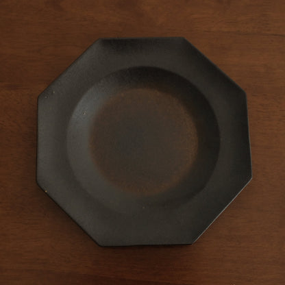 Black octagonal plate on a wooden surface