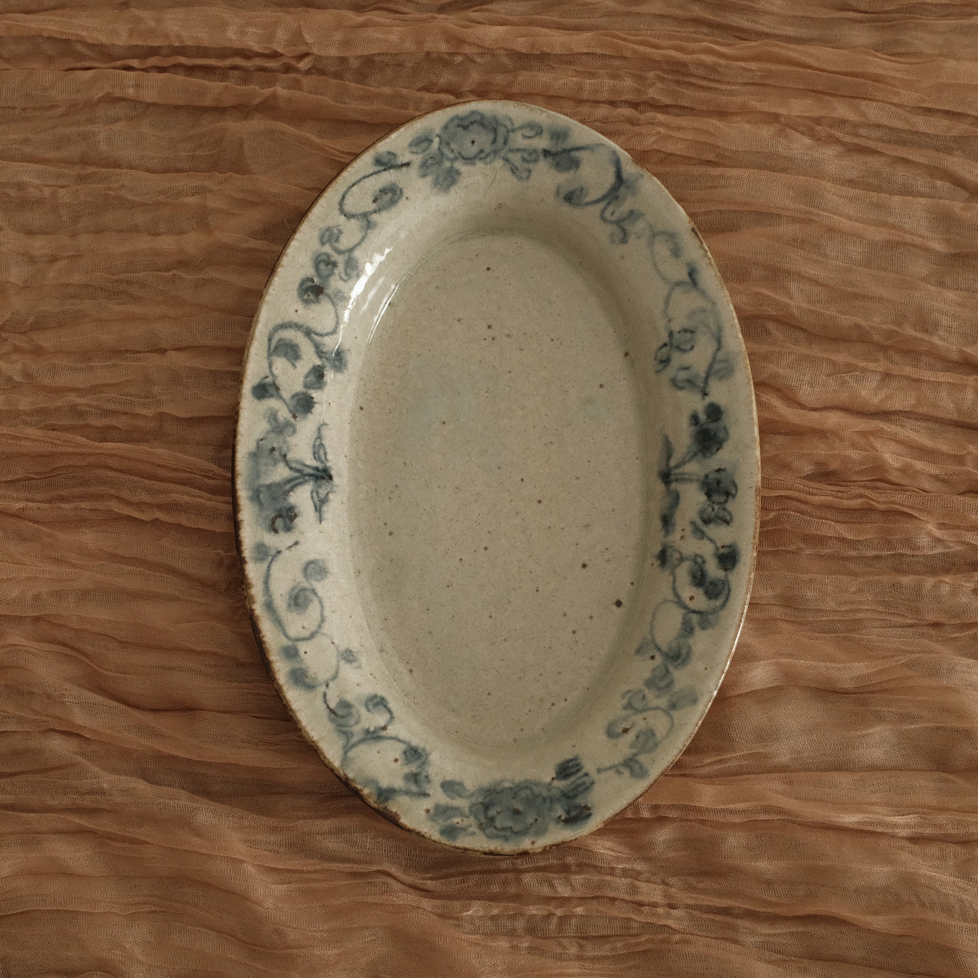 Oval ceramic dish with blue patterns on a wooden surface