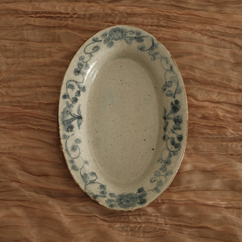 Oval ceramic dish with blue patterns on a wooden surface