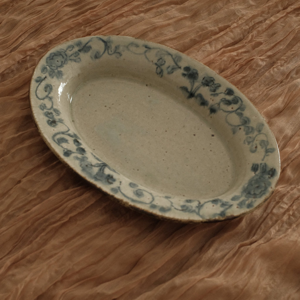Oval ceramic dish with floral patterns on a crumpled brown paper background