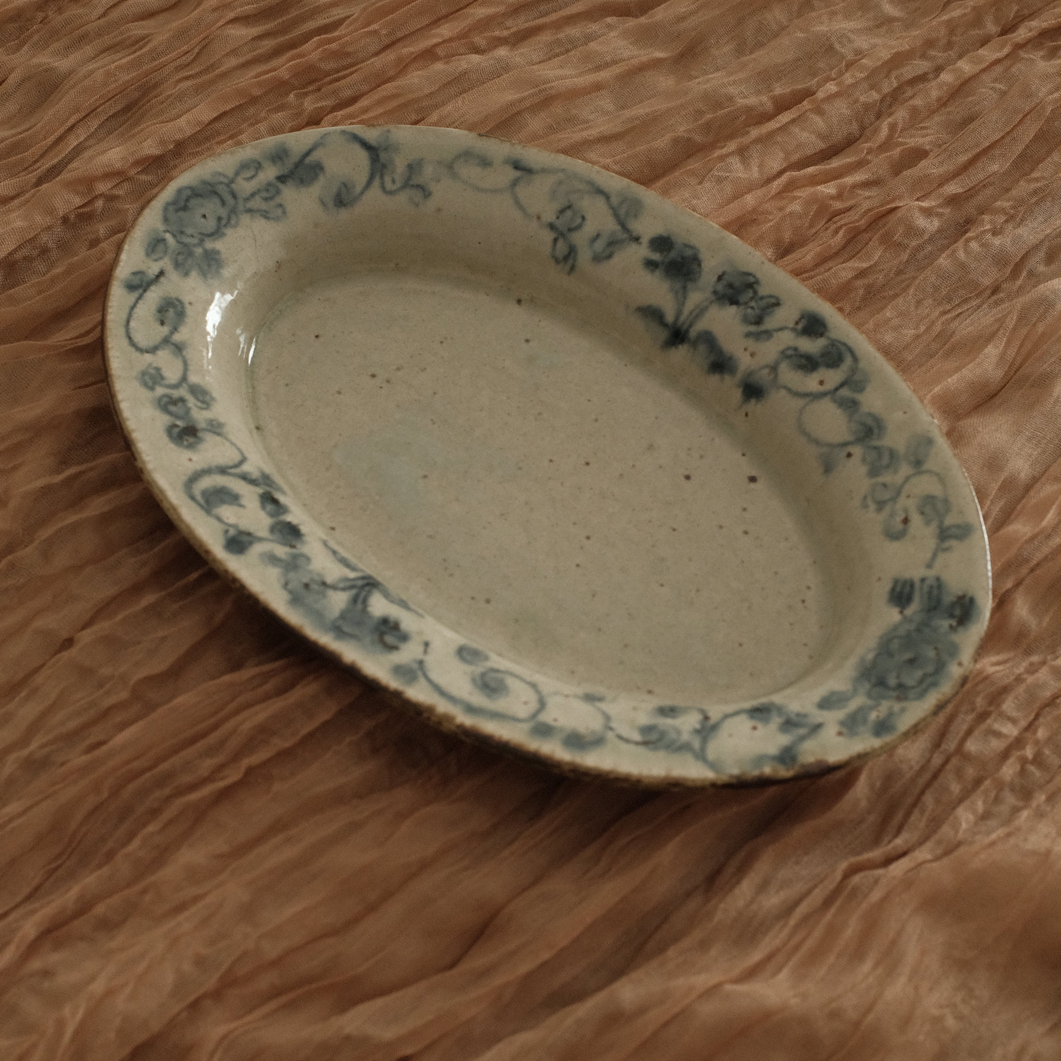 Oval ceramic dish with floral patterns on a crumpled brown paper background