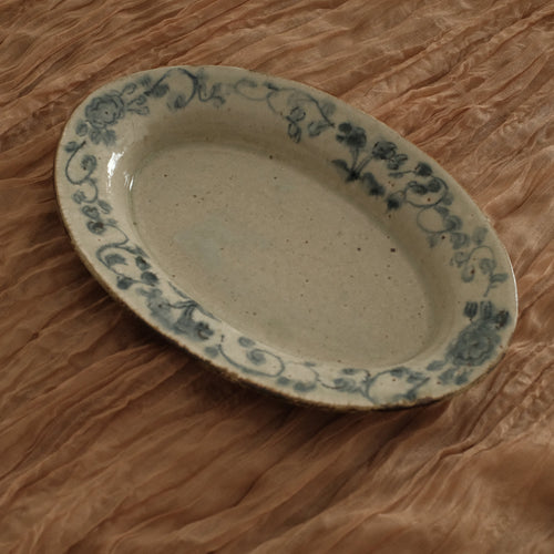 Oval ceramic dish with floral patterns on a crumpled brown paper background