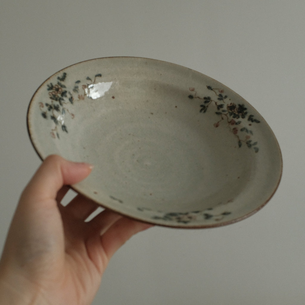 Hand holding a ceramic bowl with decorative elements against a plain background