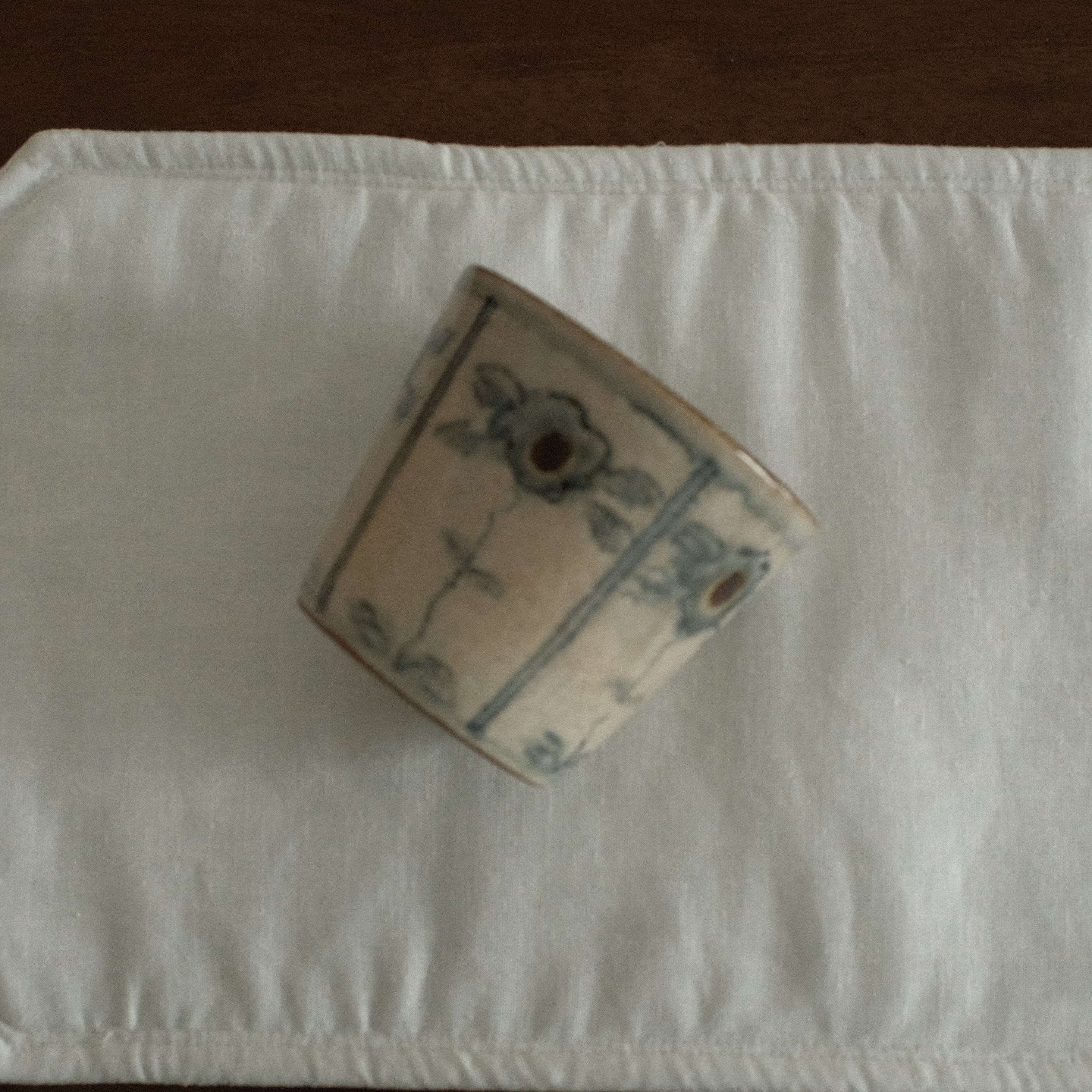Small box with decorative patterns on a white rectangular pad on a dark surface