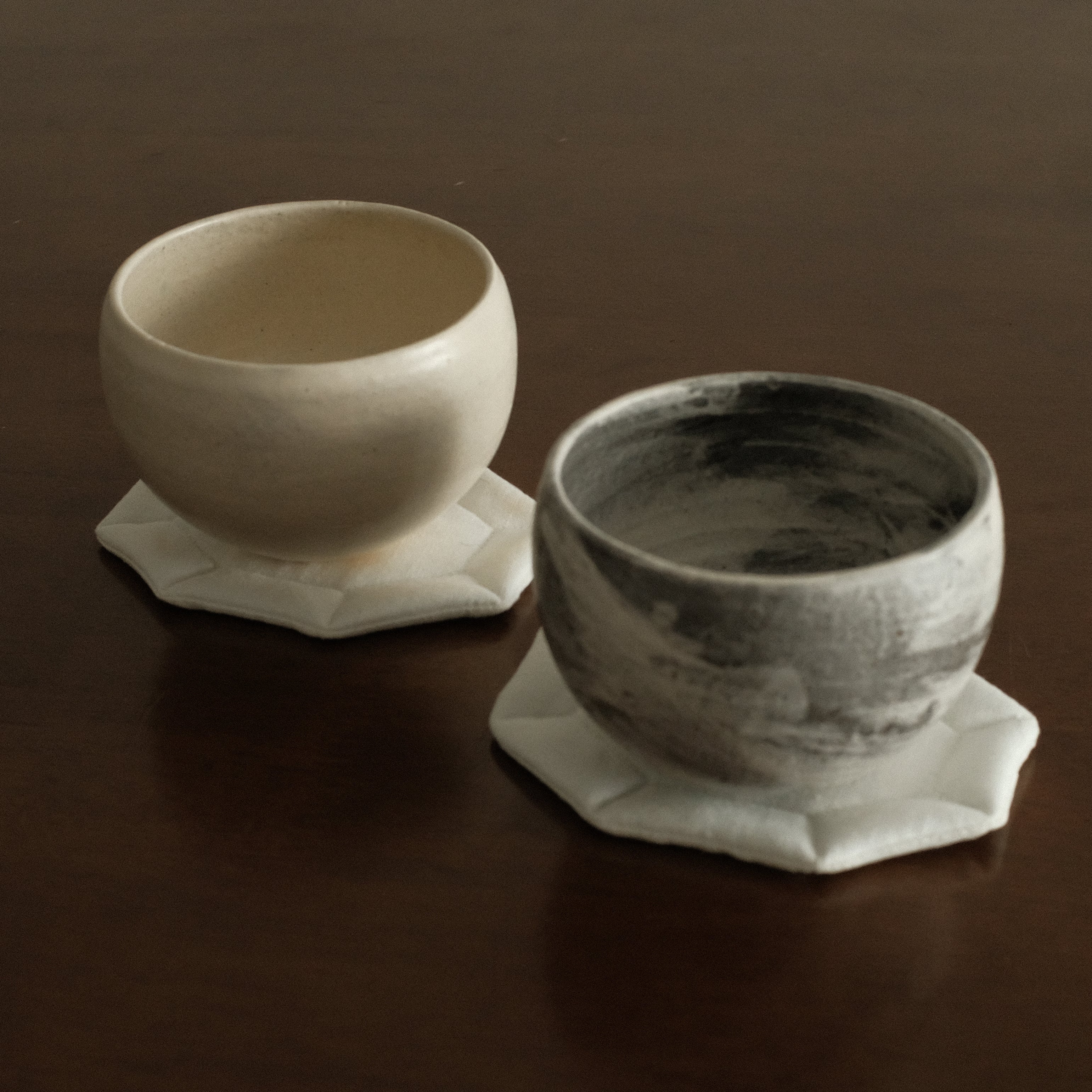 Two white and grey ceramic bowls on a dark surface