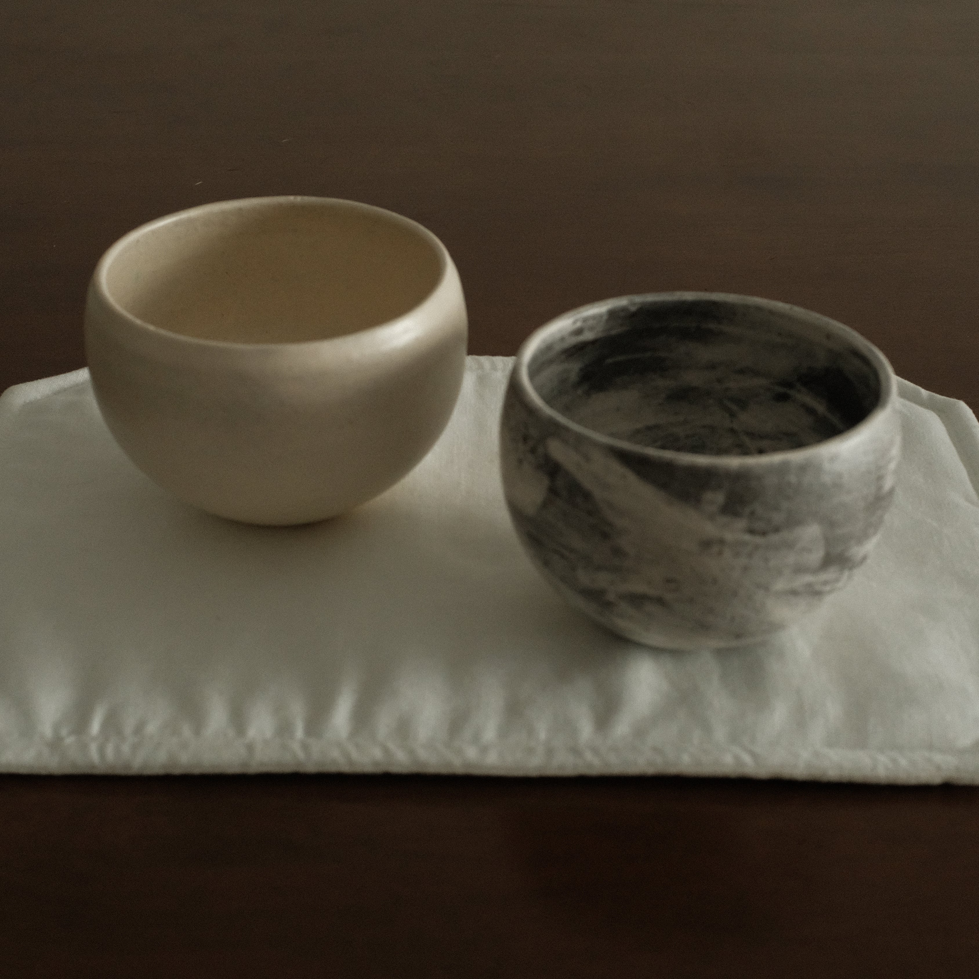 Two ceramic bowls on a square white tray against a dark background