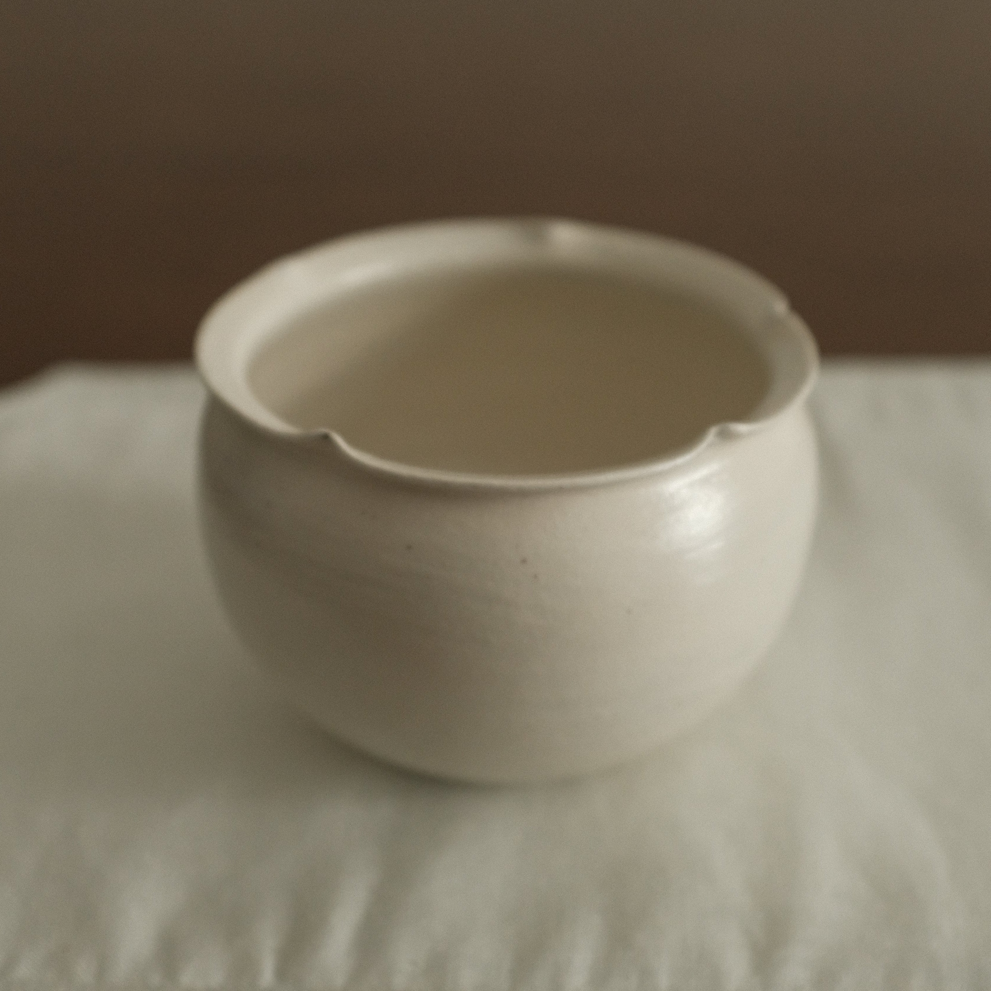 White ceramic cup on a textured surface with a neutral background