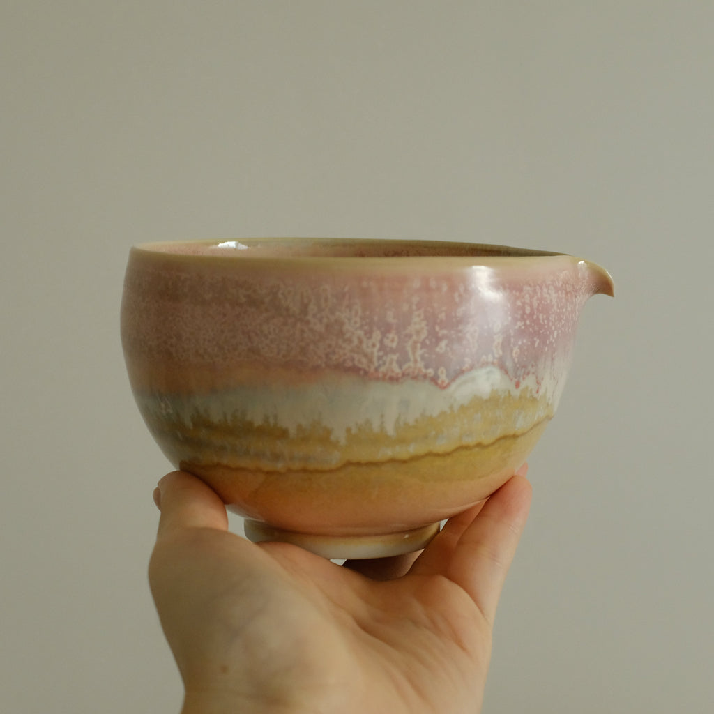 Hand holding a ceramic bowl with a gradient finish against a plain background