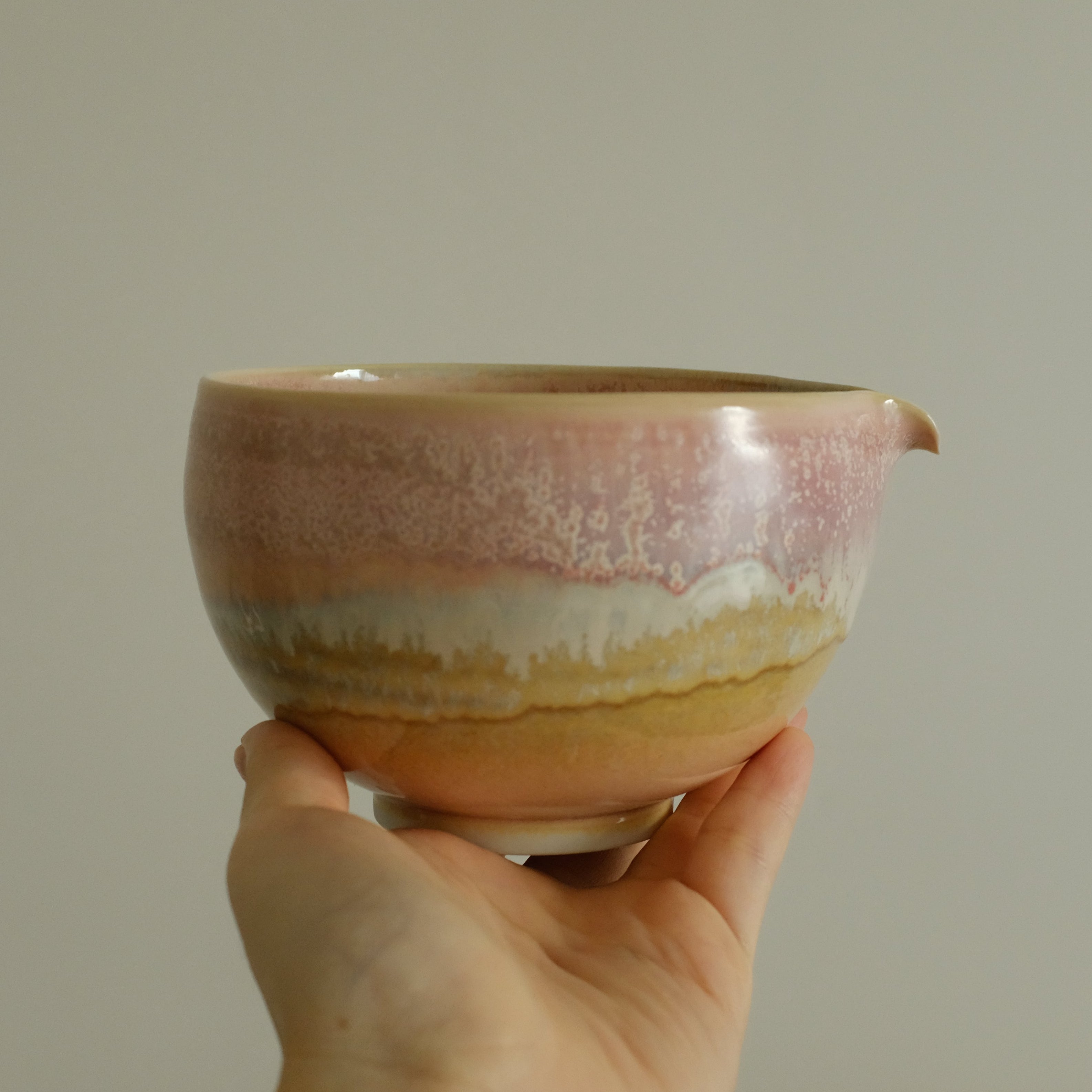 Hand holding a ceramic bowl with a gradient finish against a plain background