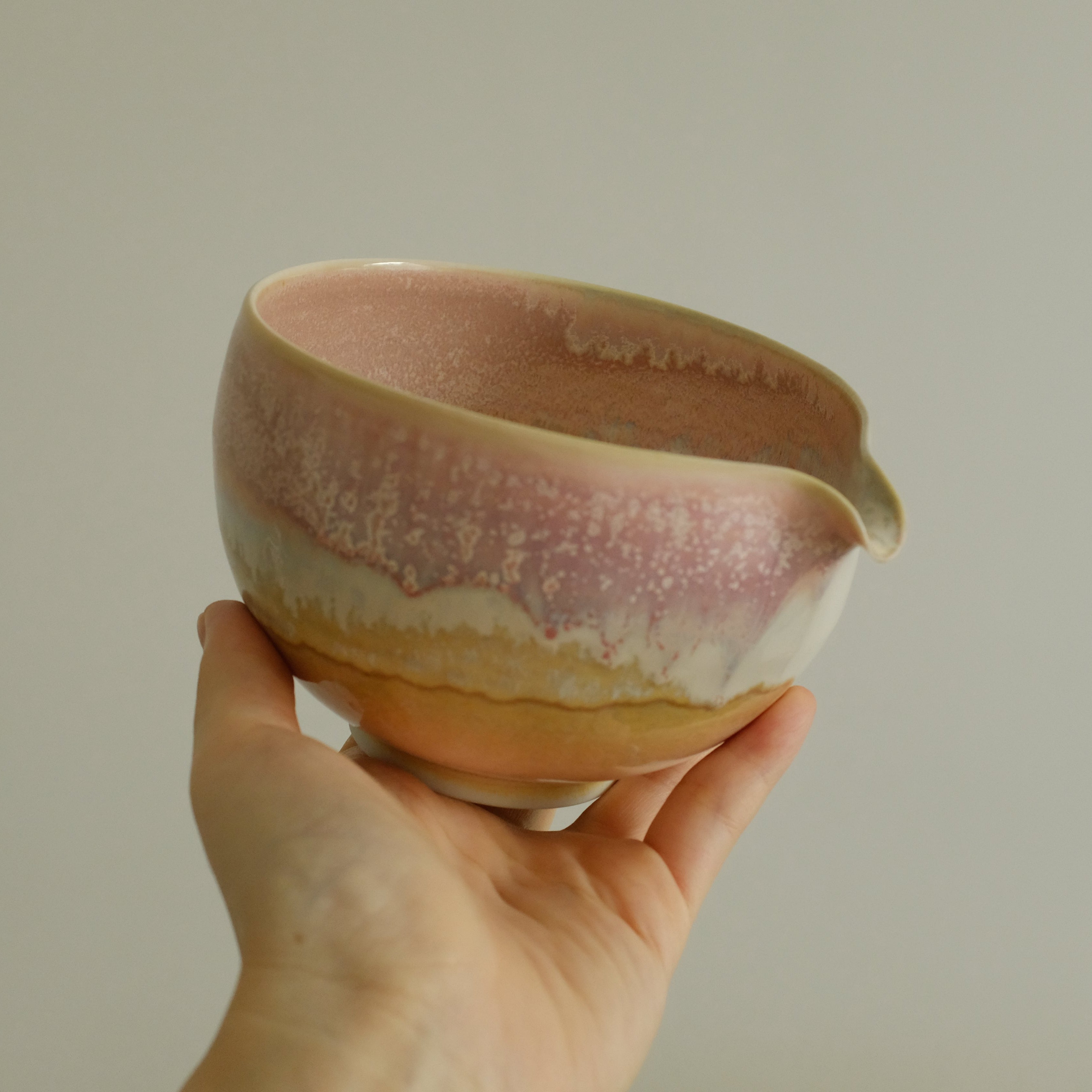 Hand holding a ceramic bowl with a gradient finish against a plain background