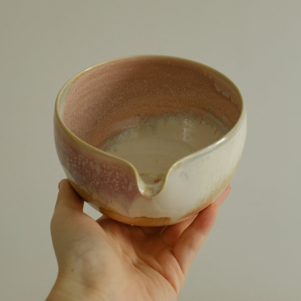 Hand holding a ceramic bowl with a textured surface against a plain background