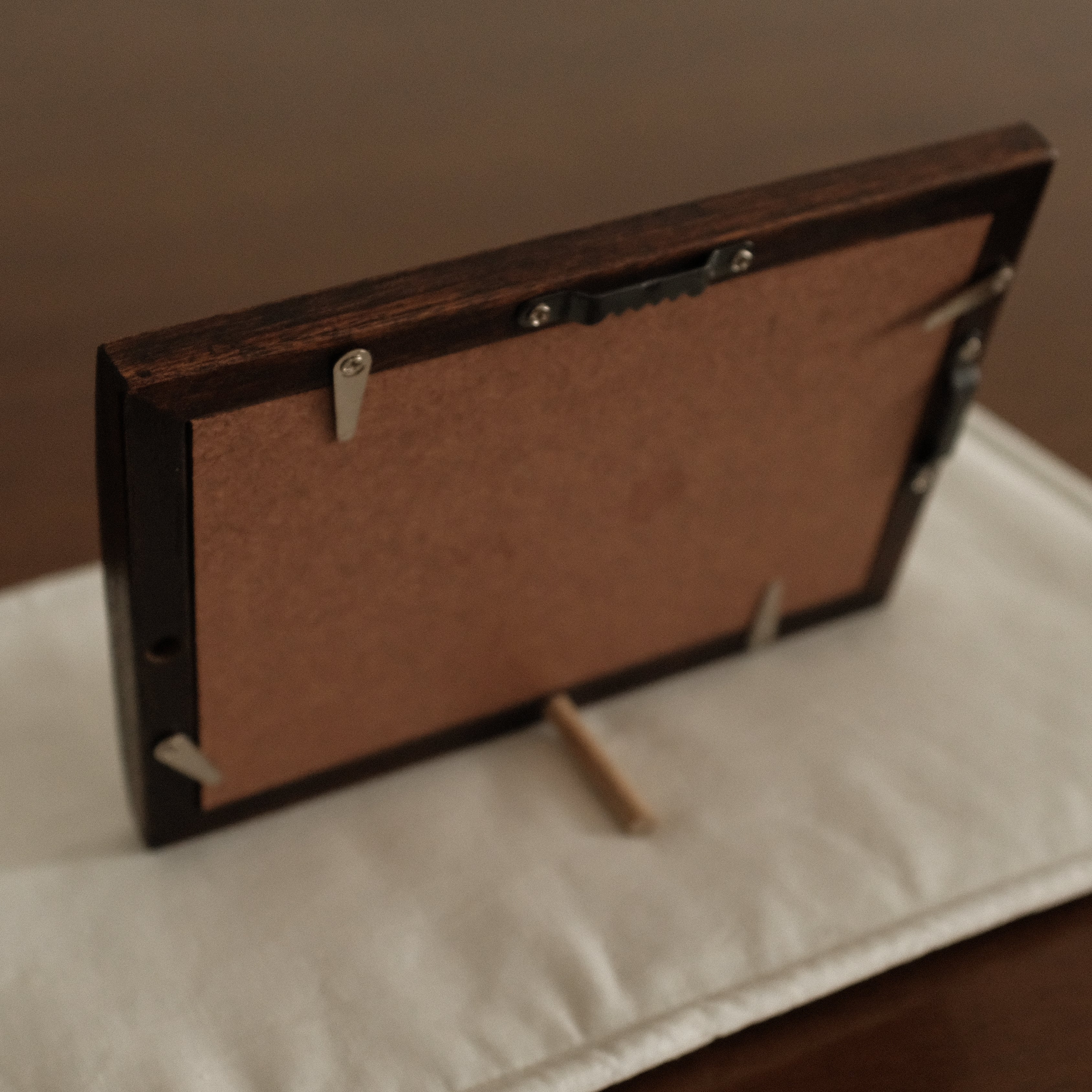 Wooden picture frame on a white stand with a brown background
