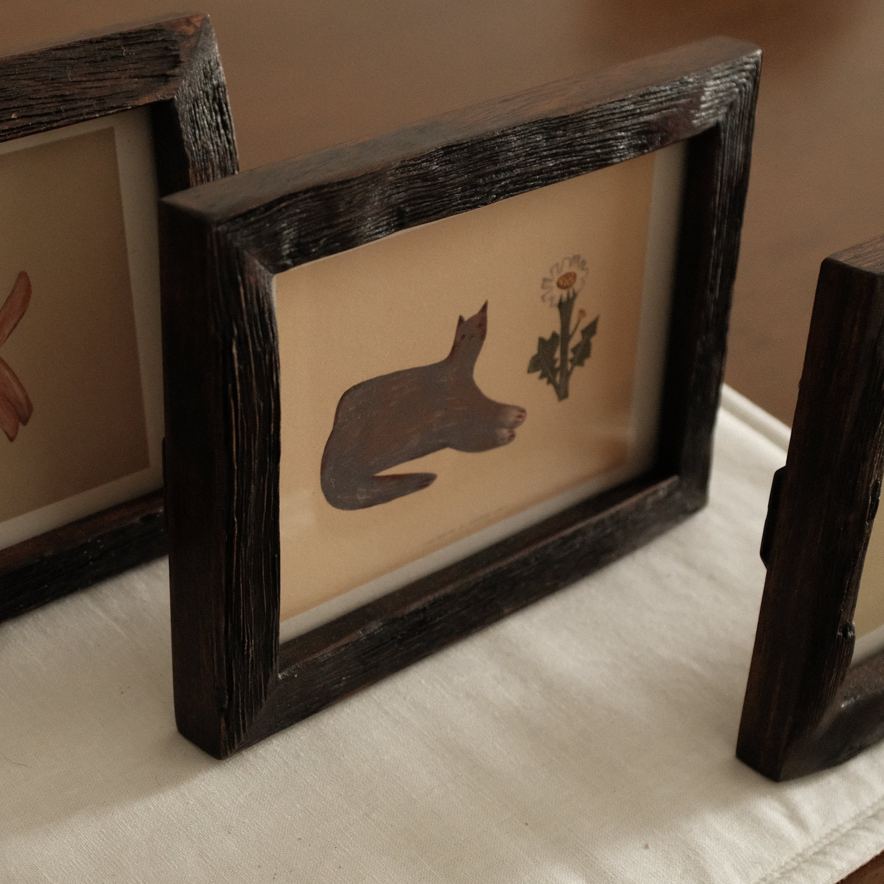 Three Teak Wood Framed artwork with a cat silhouette and flower on a white surface
