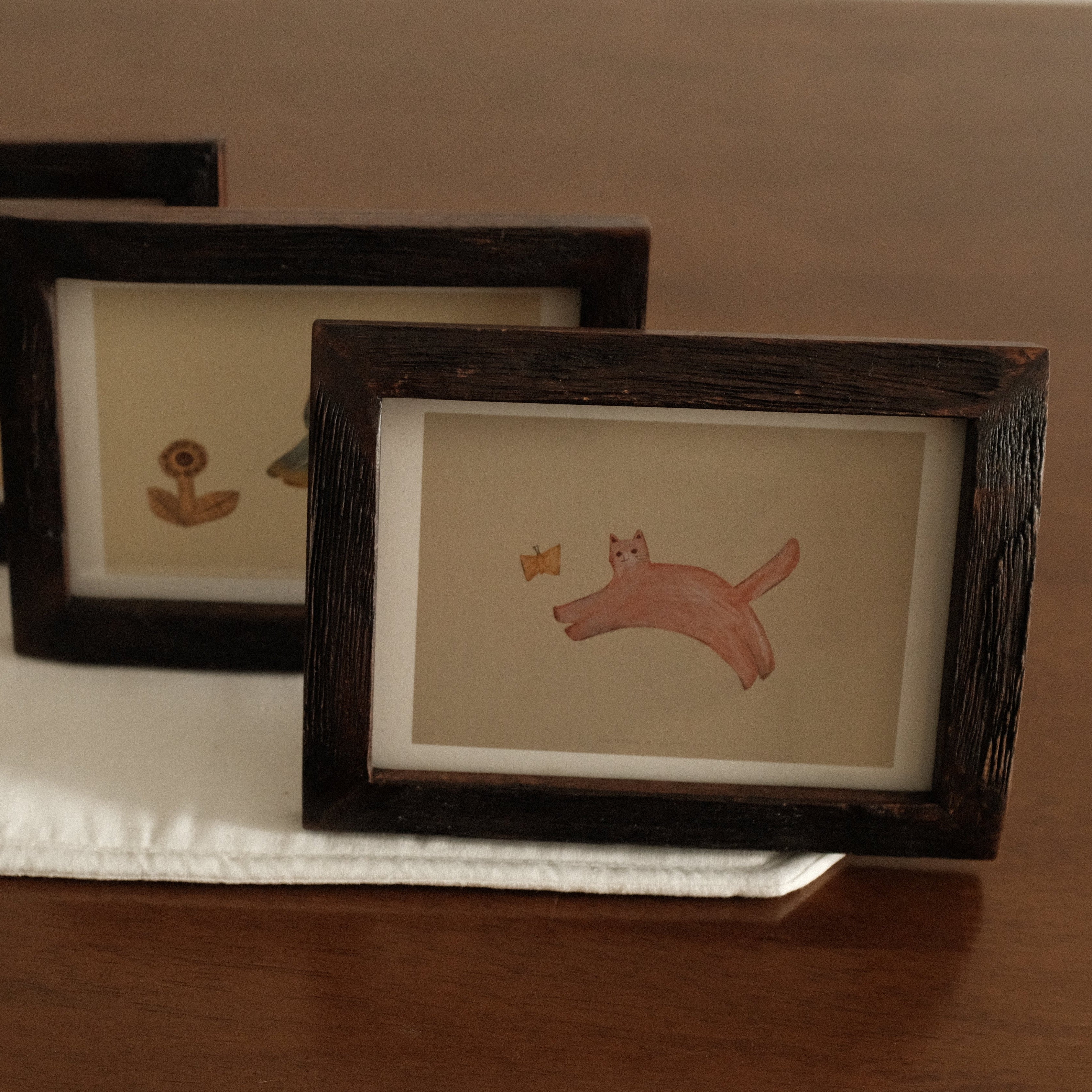Three framed prints of animals on a wooden surface