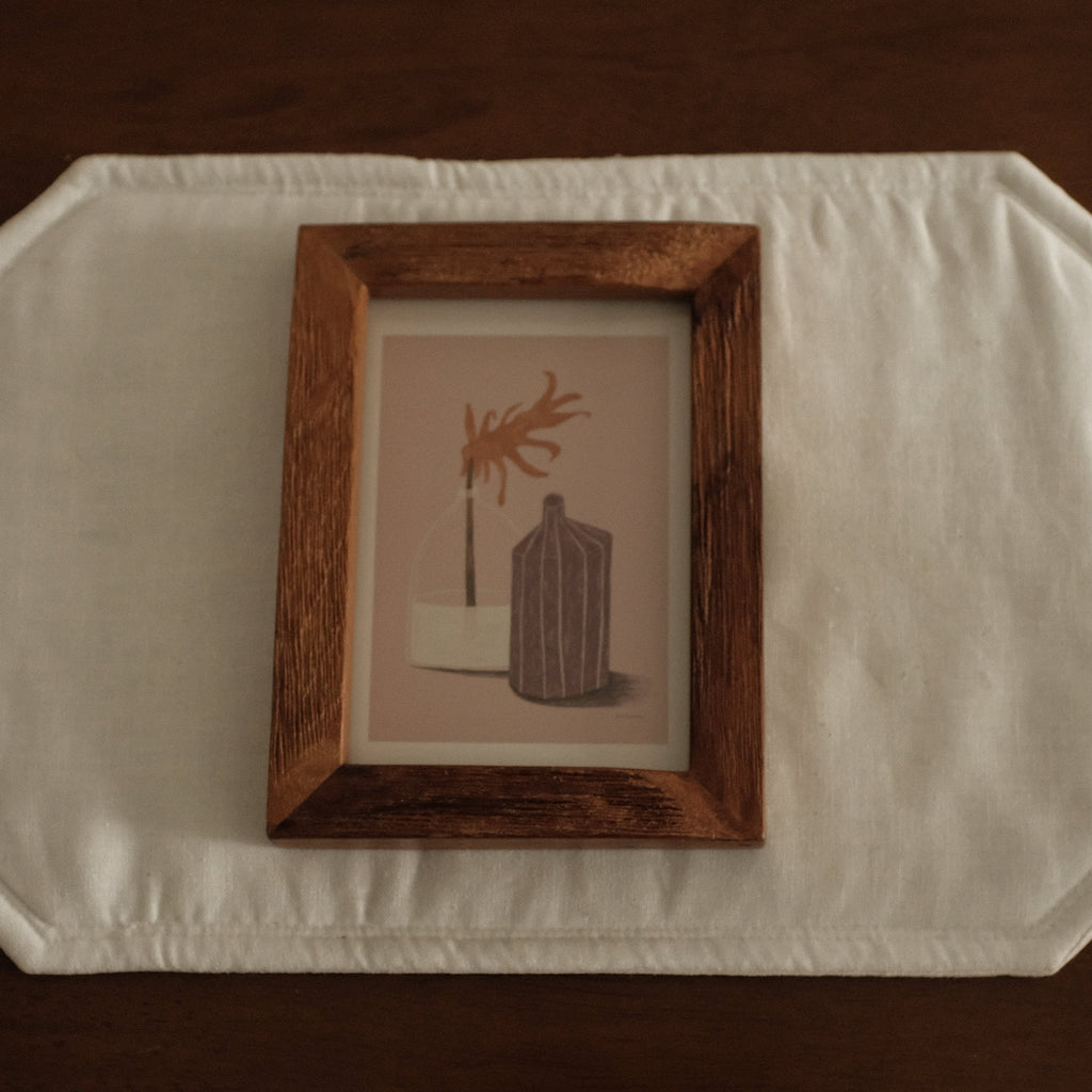 Wooden frame with a small painting on a white surface