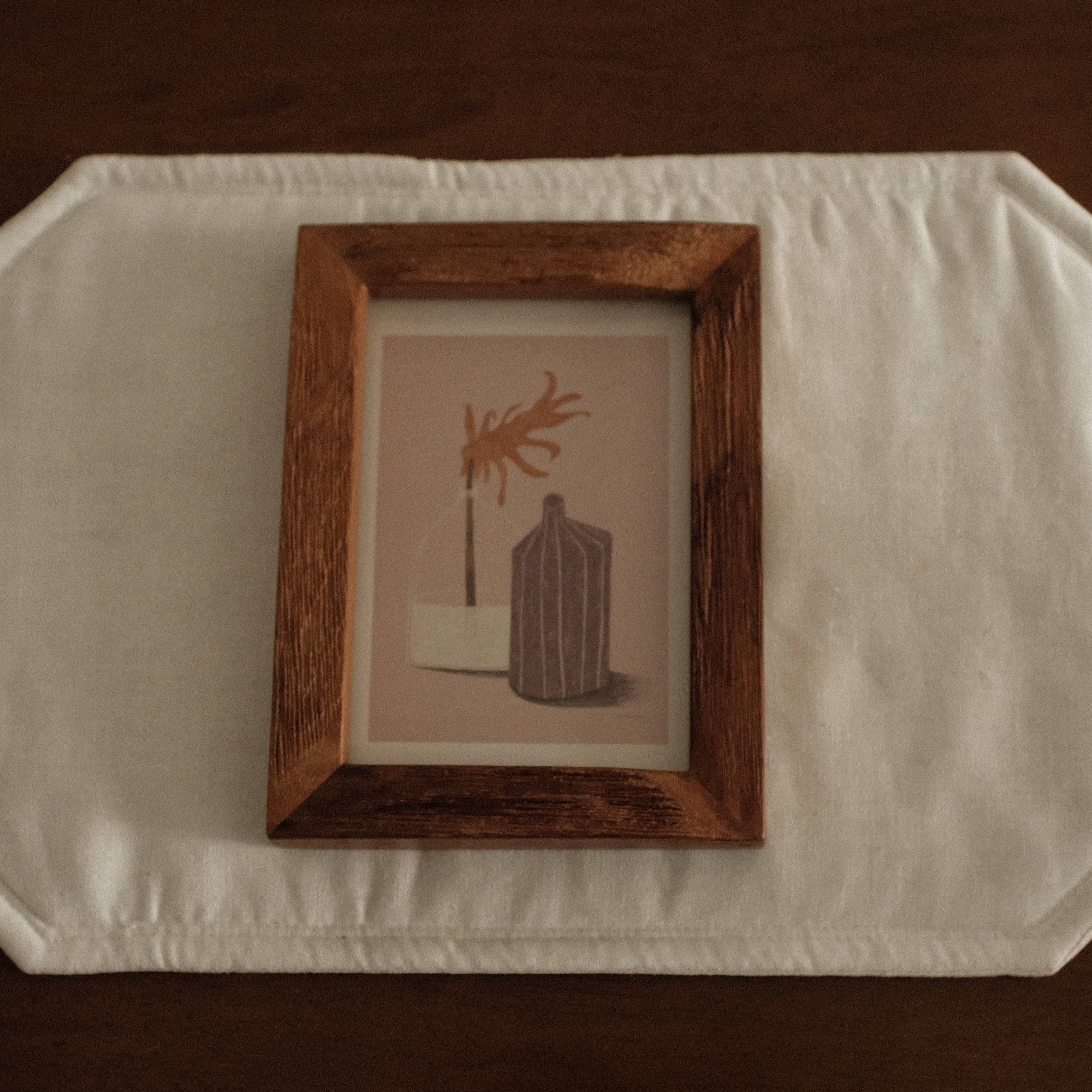 Wooden frame with a small painting on a white surface