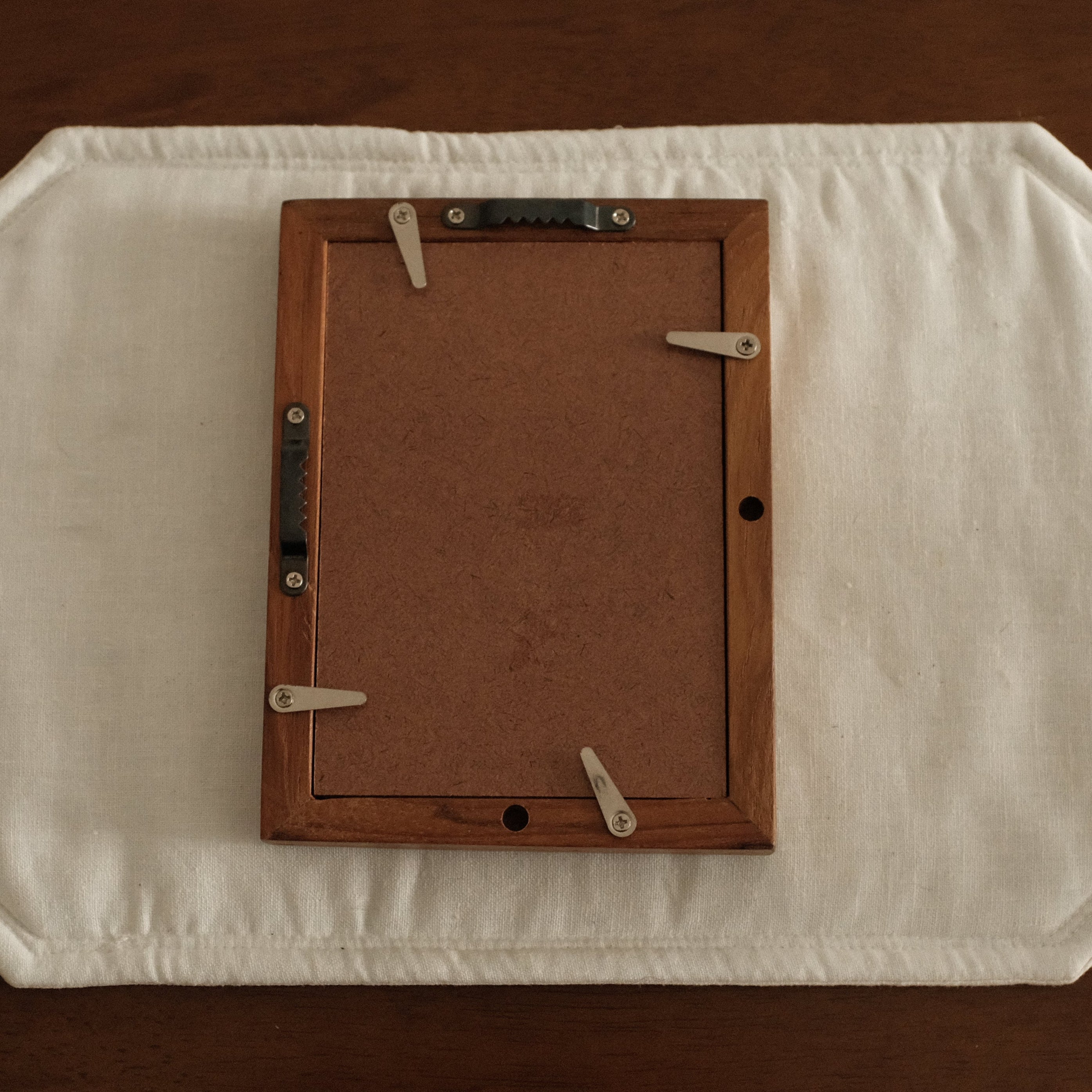 Wooden picture frame on a white cushion with a brown background