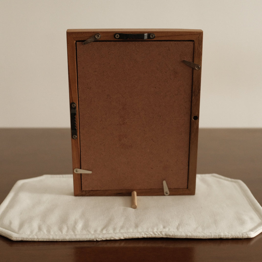 Wooden picture frame on a white cushion with a plain background