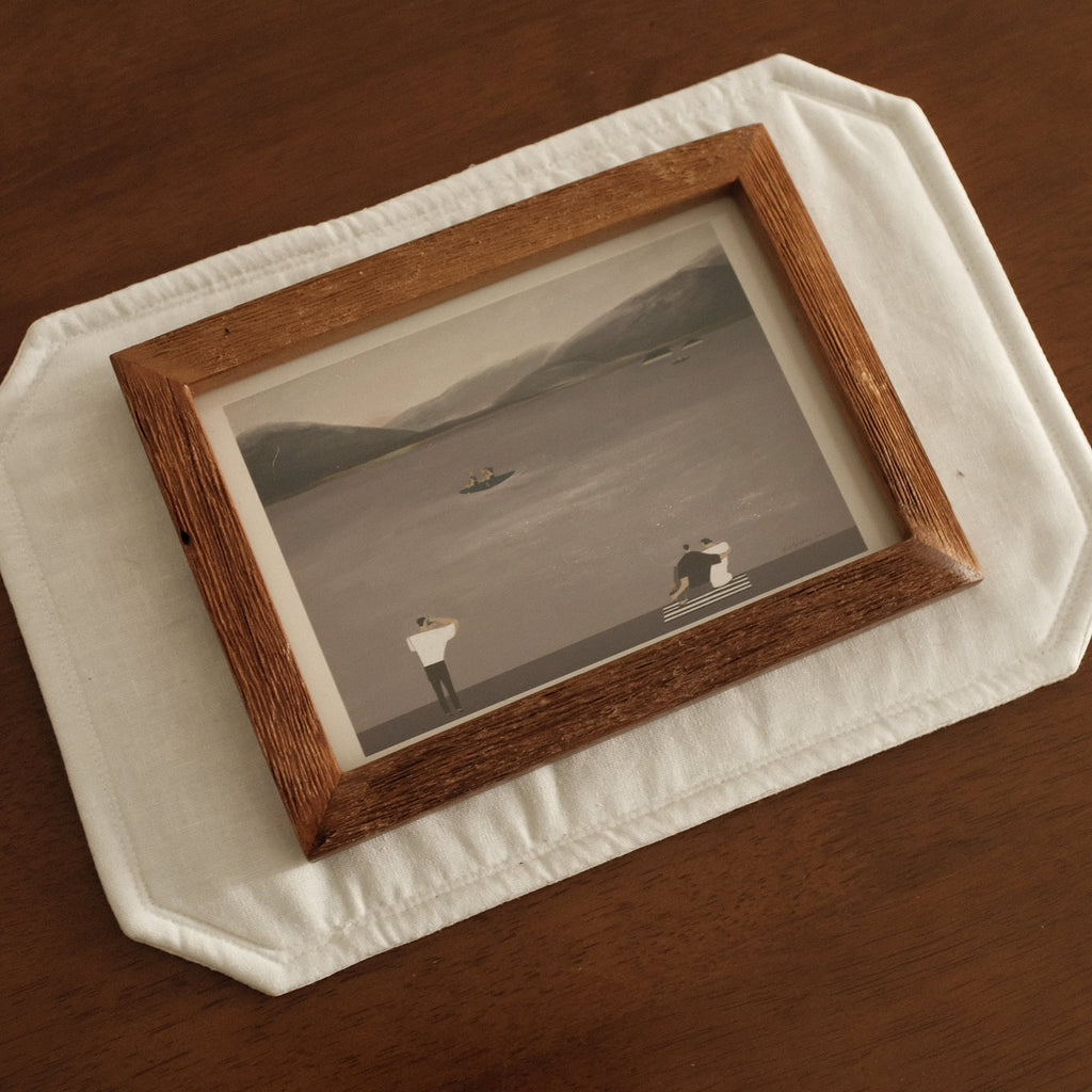 Teak Wood picture frame with a small landscape painting on a wooden surface