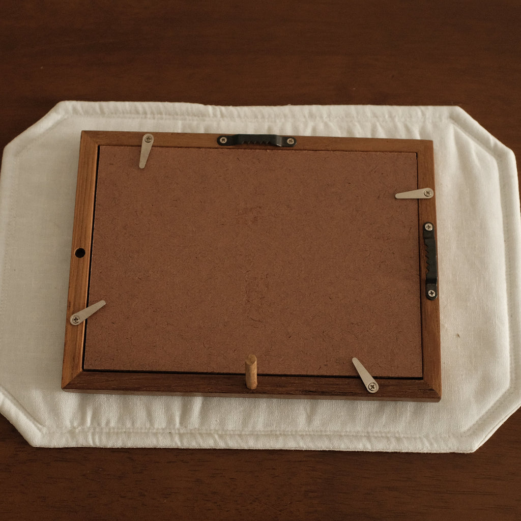 Wooden picture frame on a white tray with a brown background
