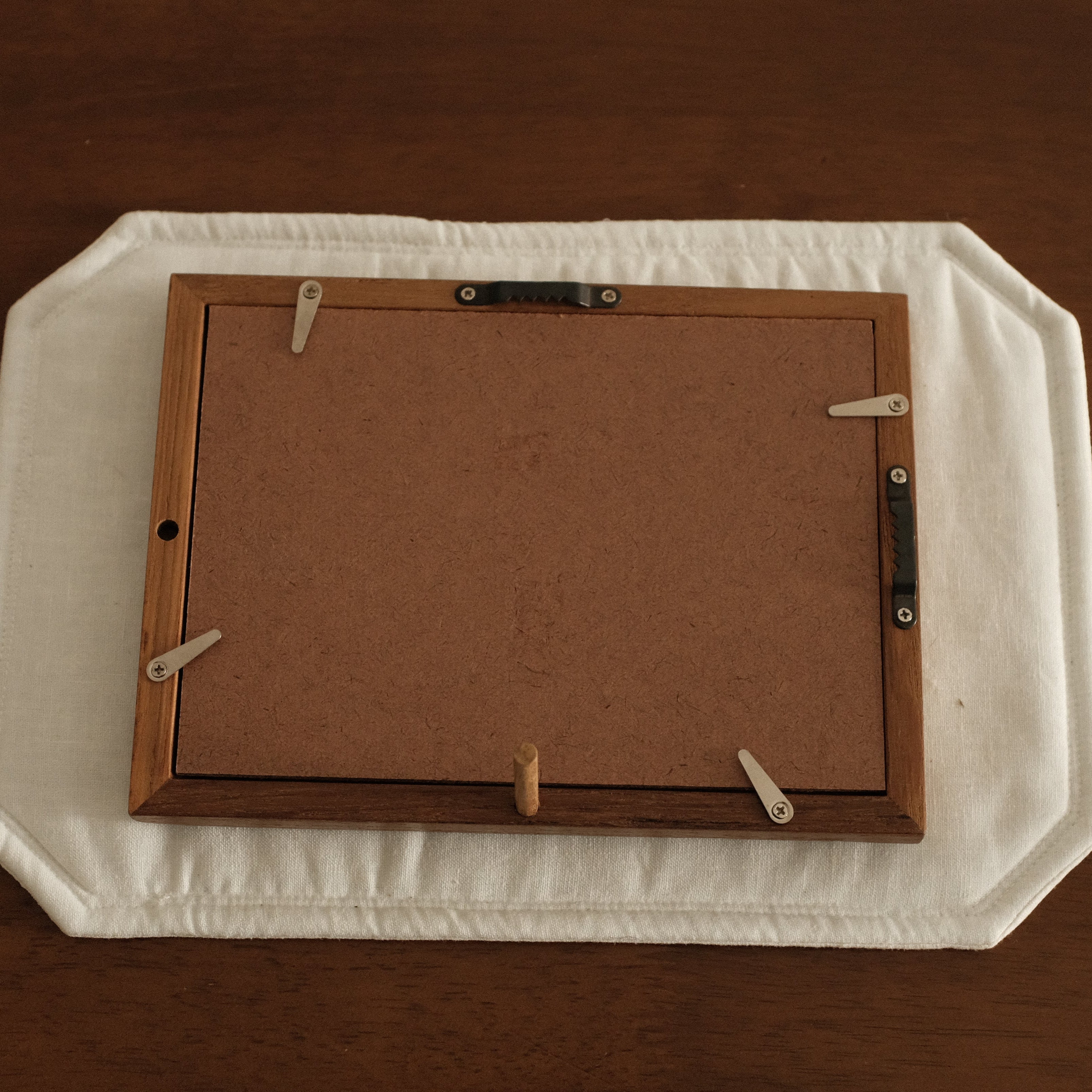 Wooden picture frame on a white tray with a brown background