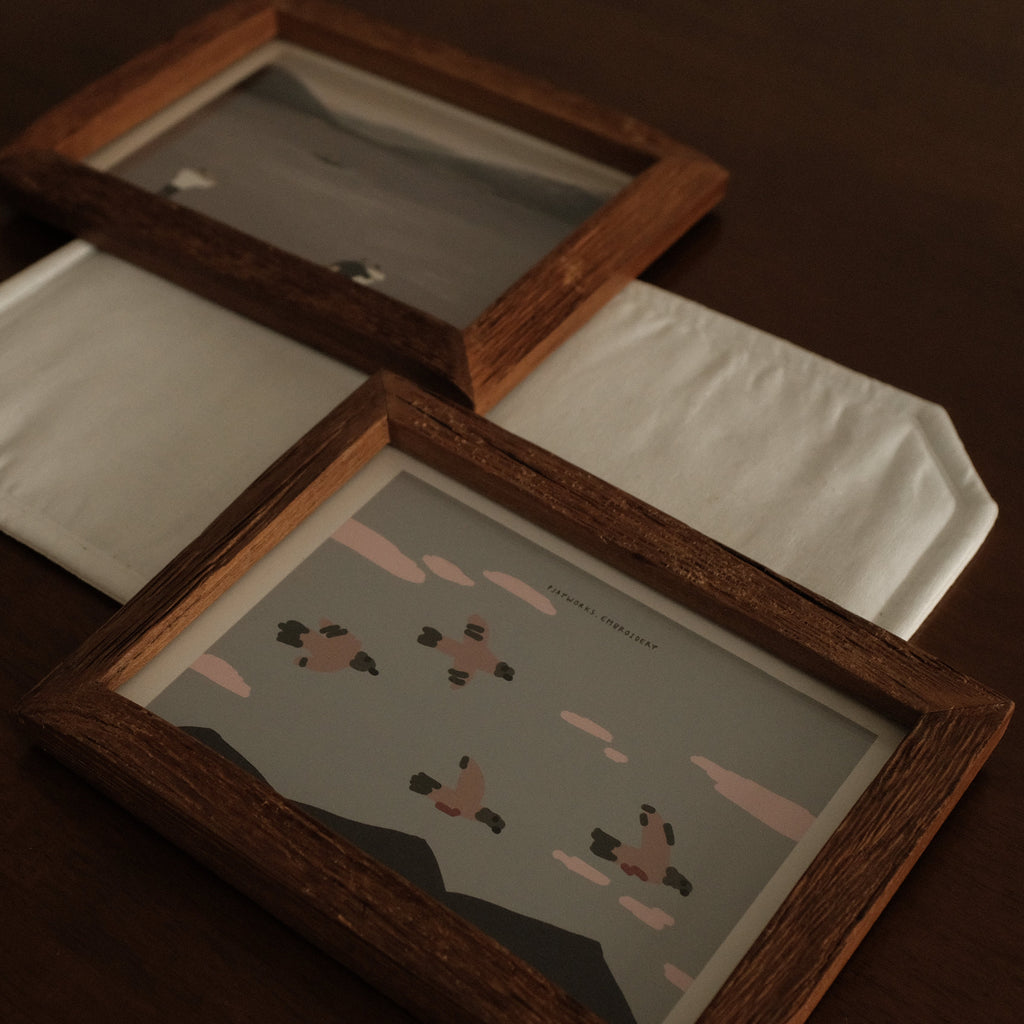 Two Teak Wood picture frames with a small illustration on a dark background