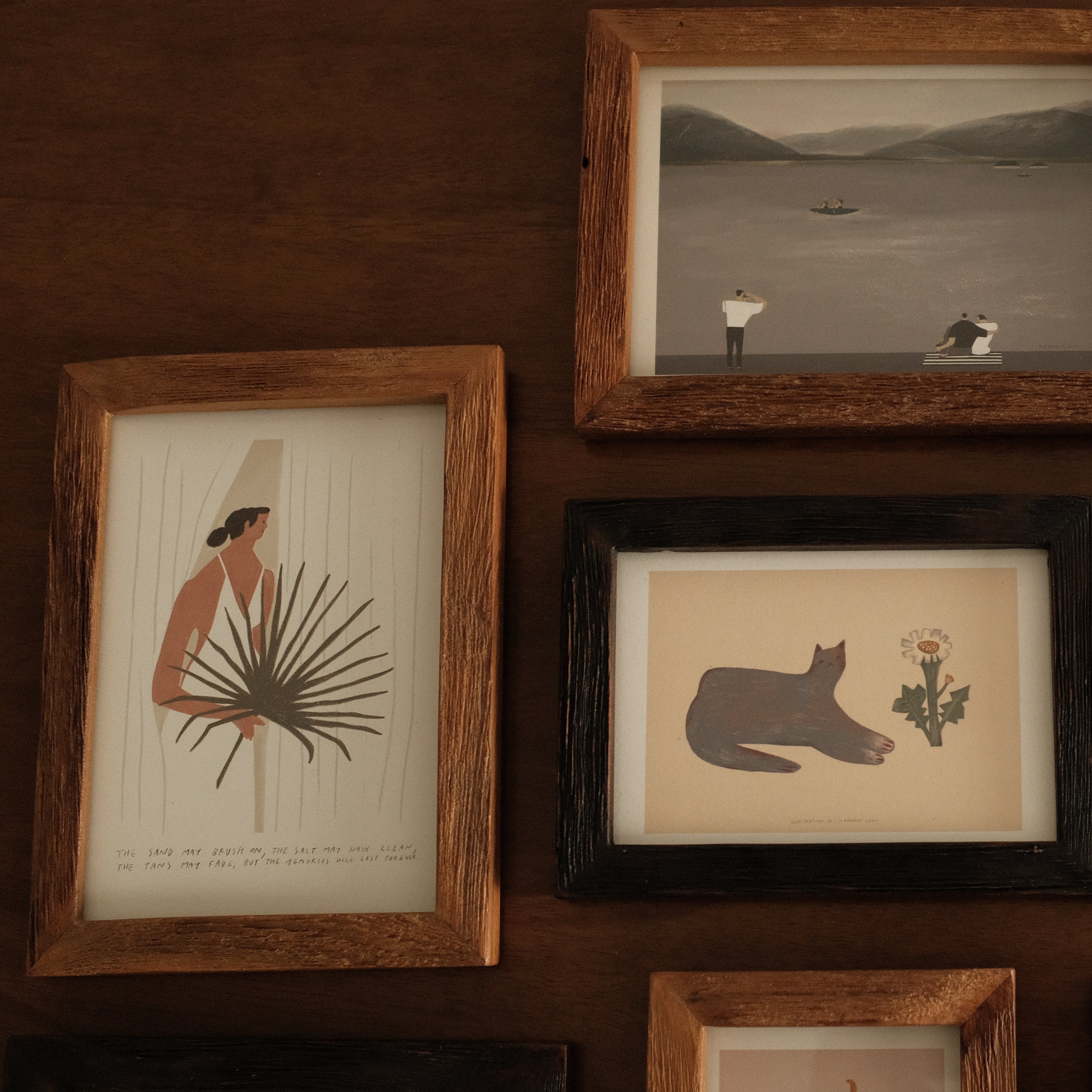 Collection of framed artworks on a wooden wall