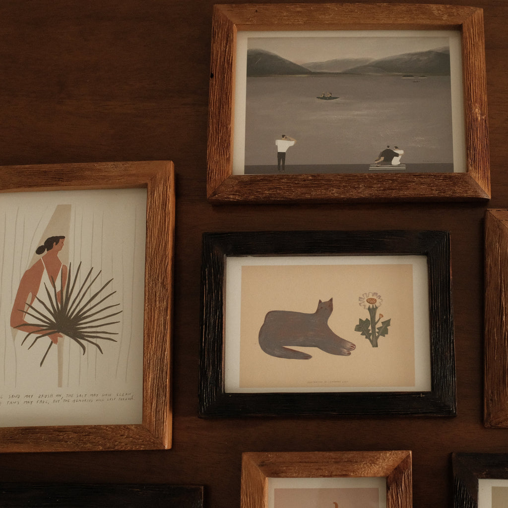 Collection of teak wood ramed artworks on a wooden wall