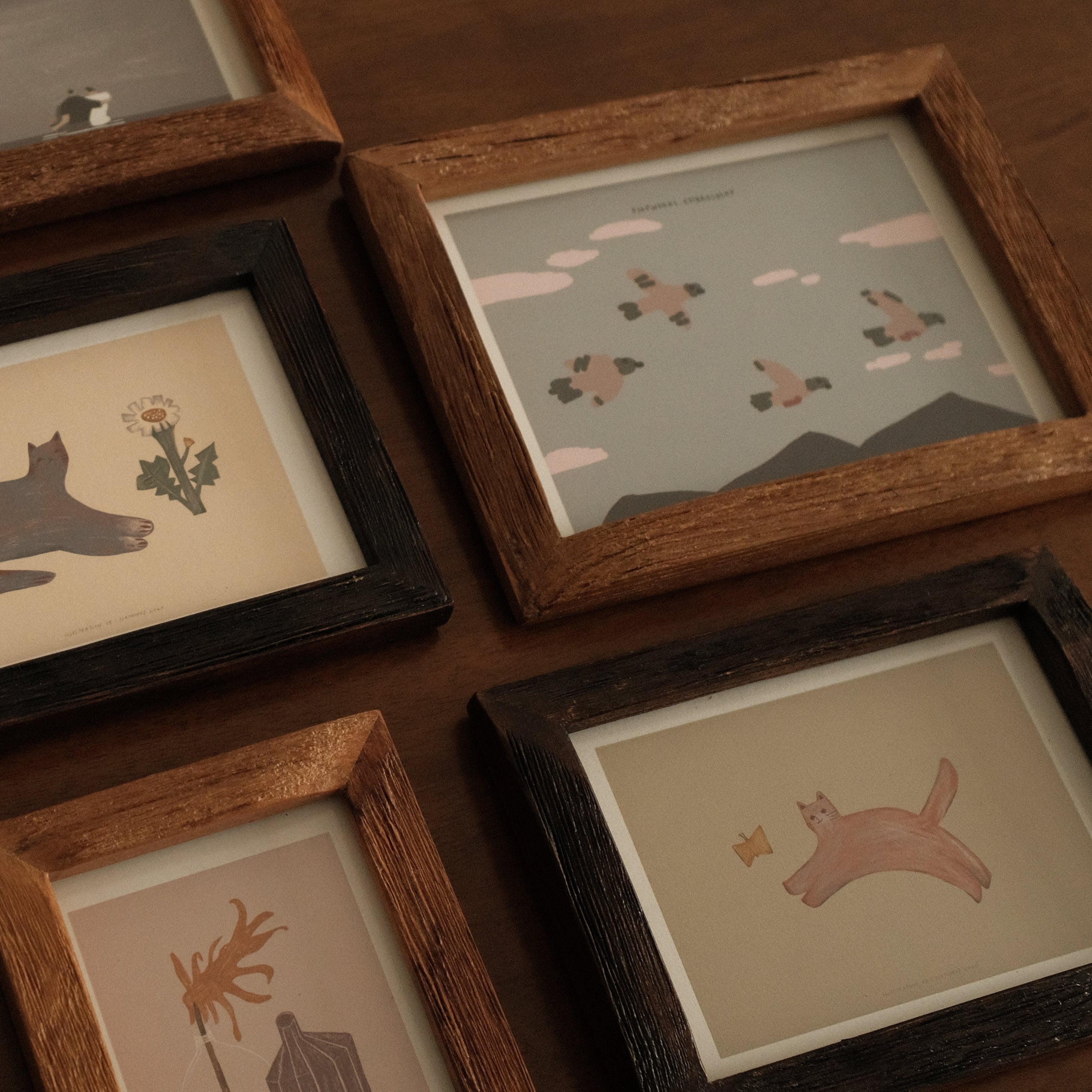 Collection of framed artworks on a wooden surface