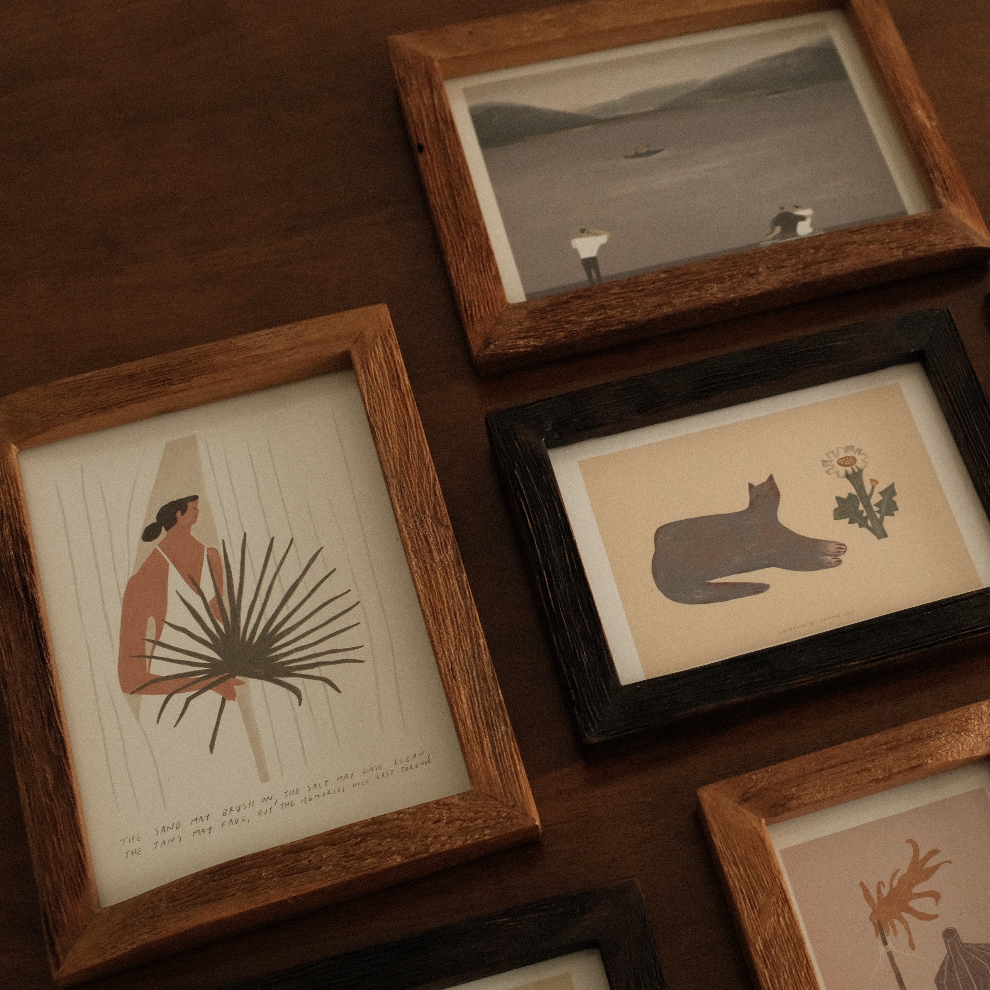 Collection of framed artworks on a wooden surface
