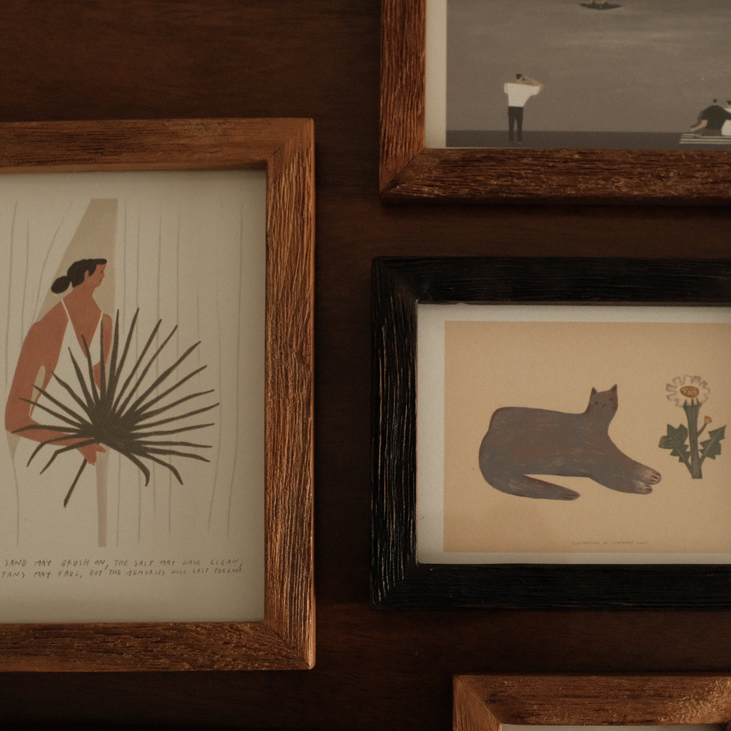 Collection of teak wood framed artworks on a wooden wall