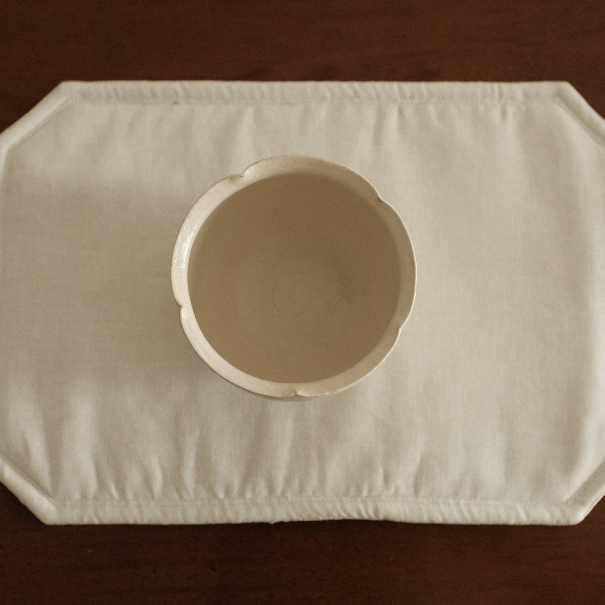 White ceramic floral rim cup on a textured white surface with a brown 