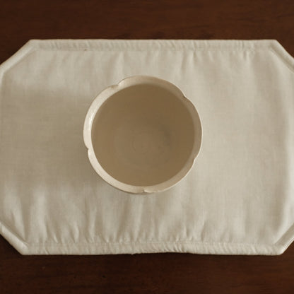 White ceramic floral rim cup on a textured white surface with a brown 