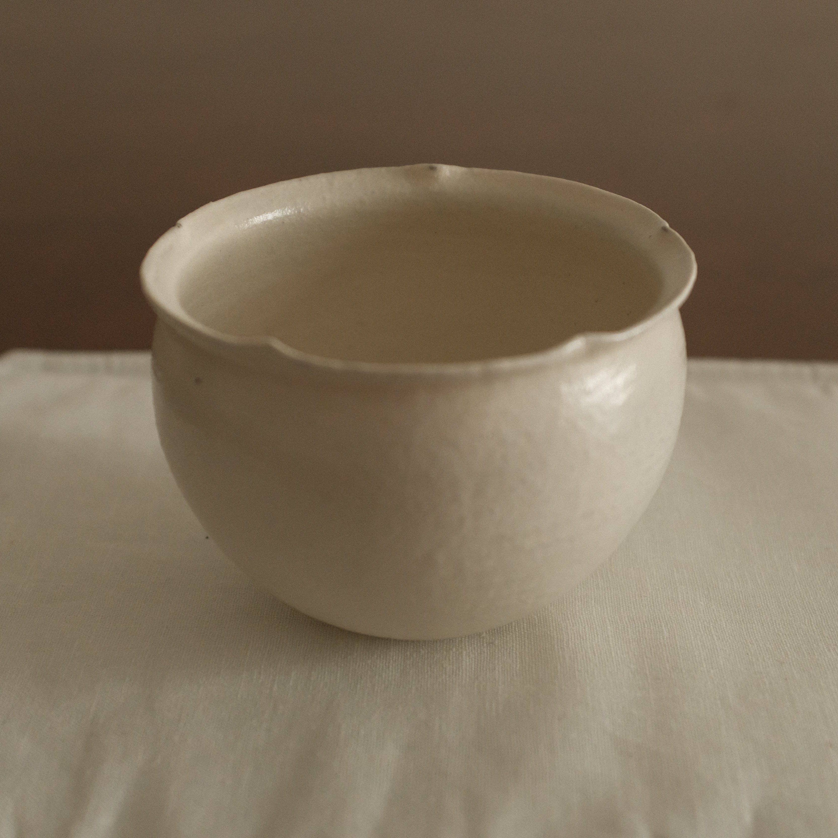 White ceramic floral rim cup on a textured white surface with a brown 