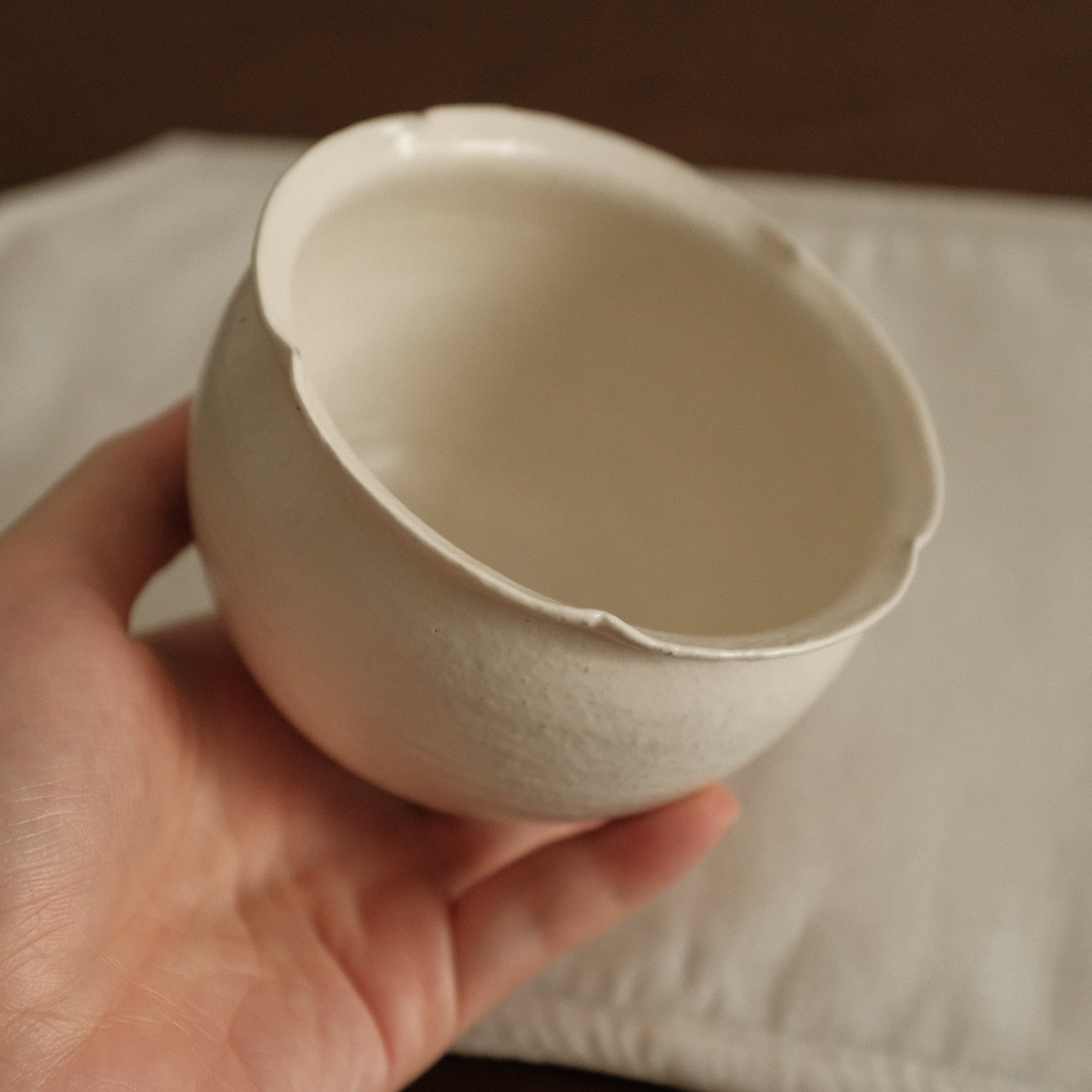Hand holding a ceramic flora rim cup against a neutral background