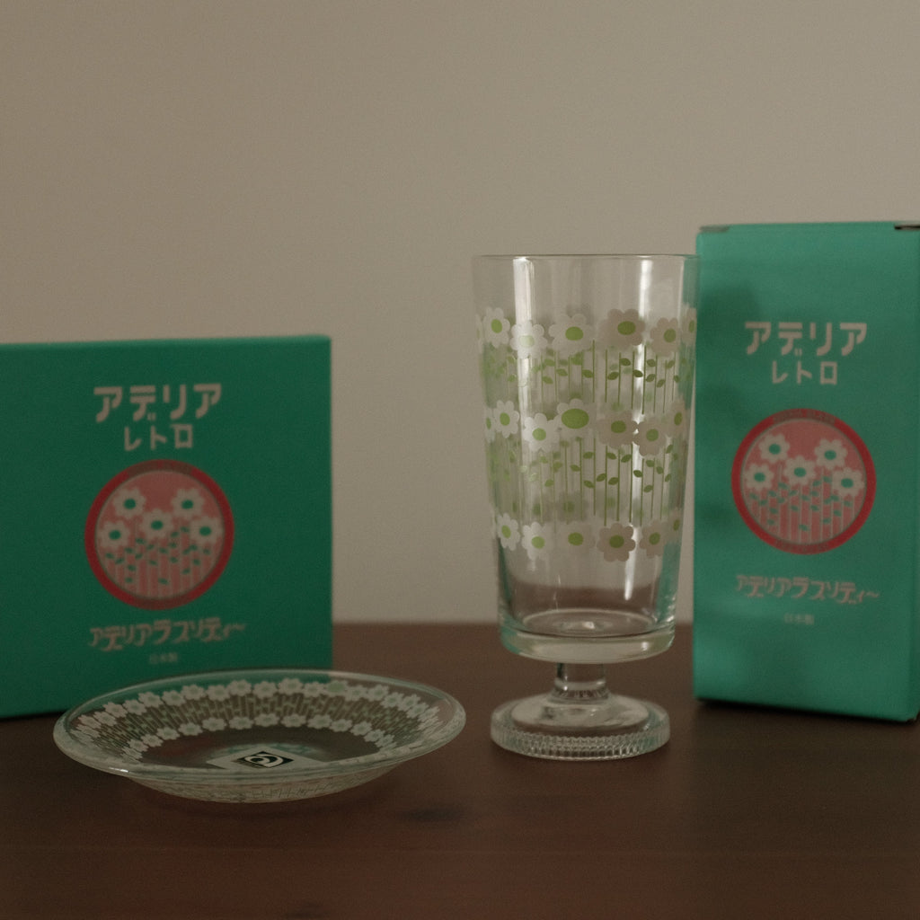 Green packaging with a red logo and a clear glass on a wooden surface.