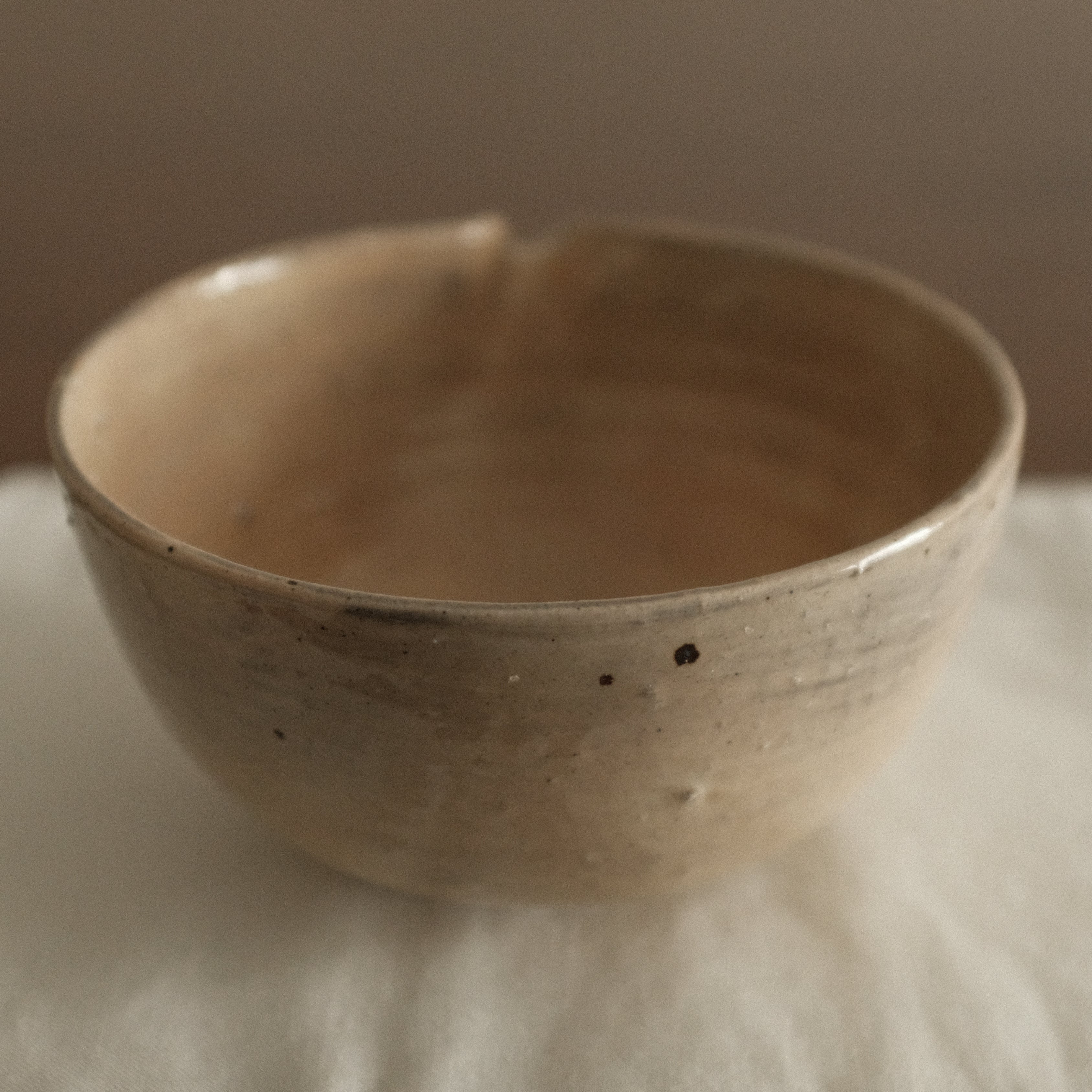 Ceramic bowl on a white cloth with a wooden background