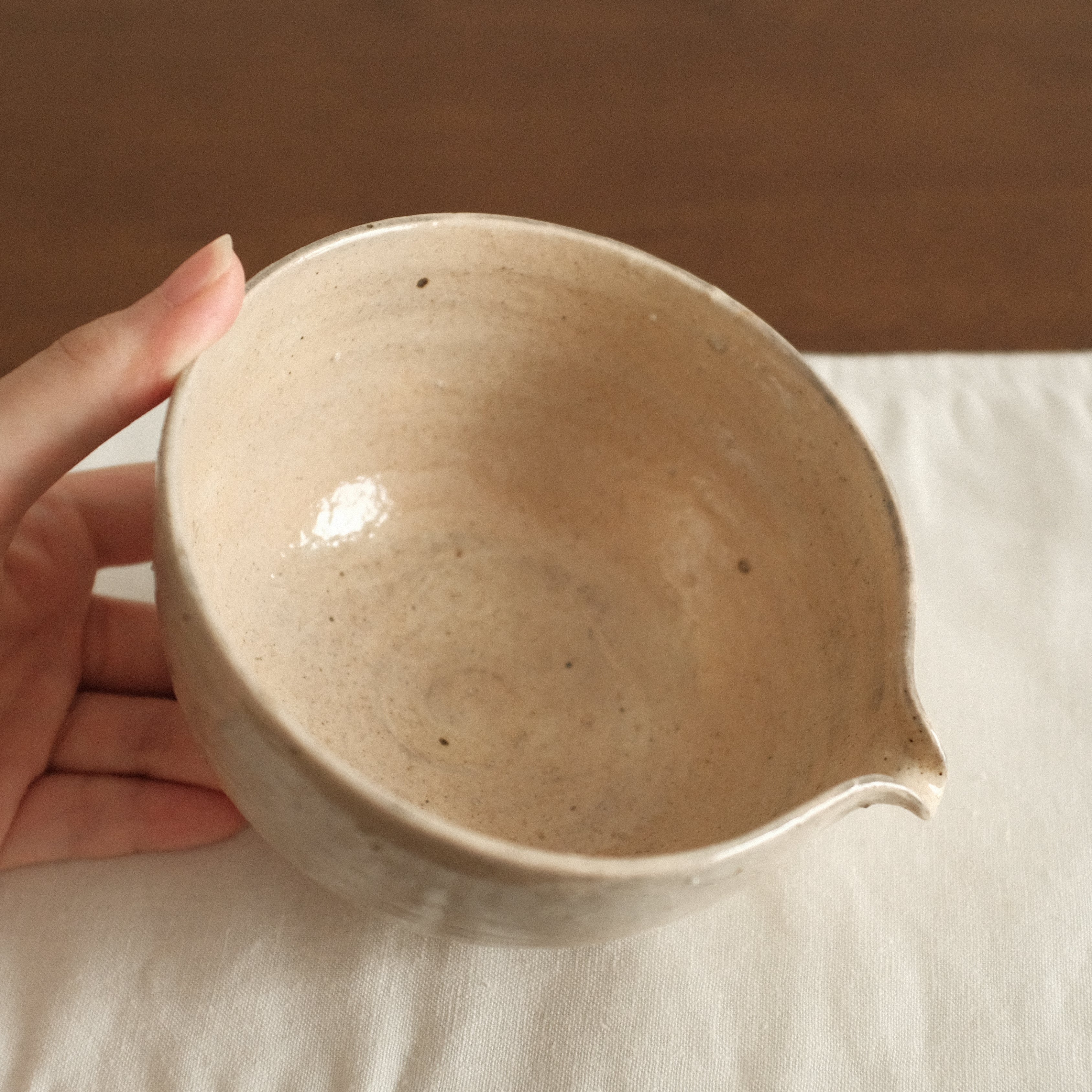 Ceramic bowl on a white cloth with a wooden background