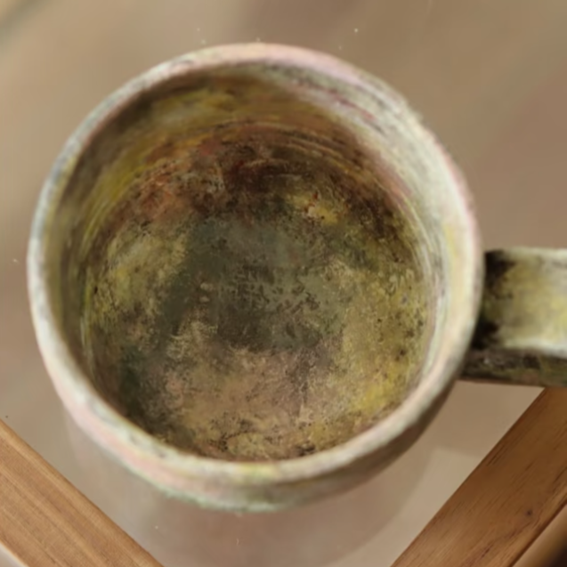 Vintage ceramic mug with a textured surface on a reflective surface.