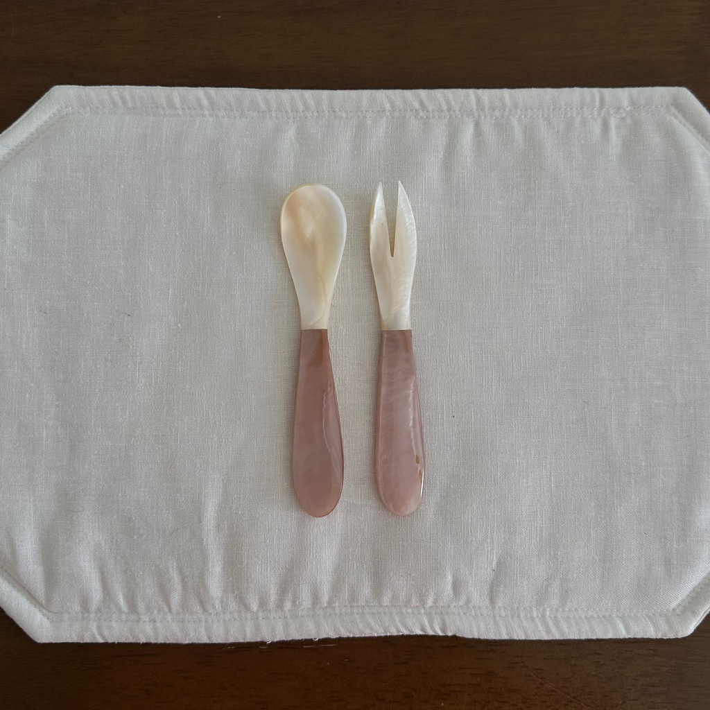 Mother of Pearl Spoon and Fork Pink and White on white placemat on wooden background