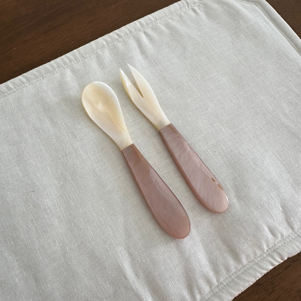 Mother of Pearl Spoon and Fork Pink and White on white placemat on wooden background