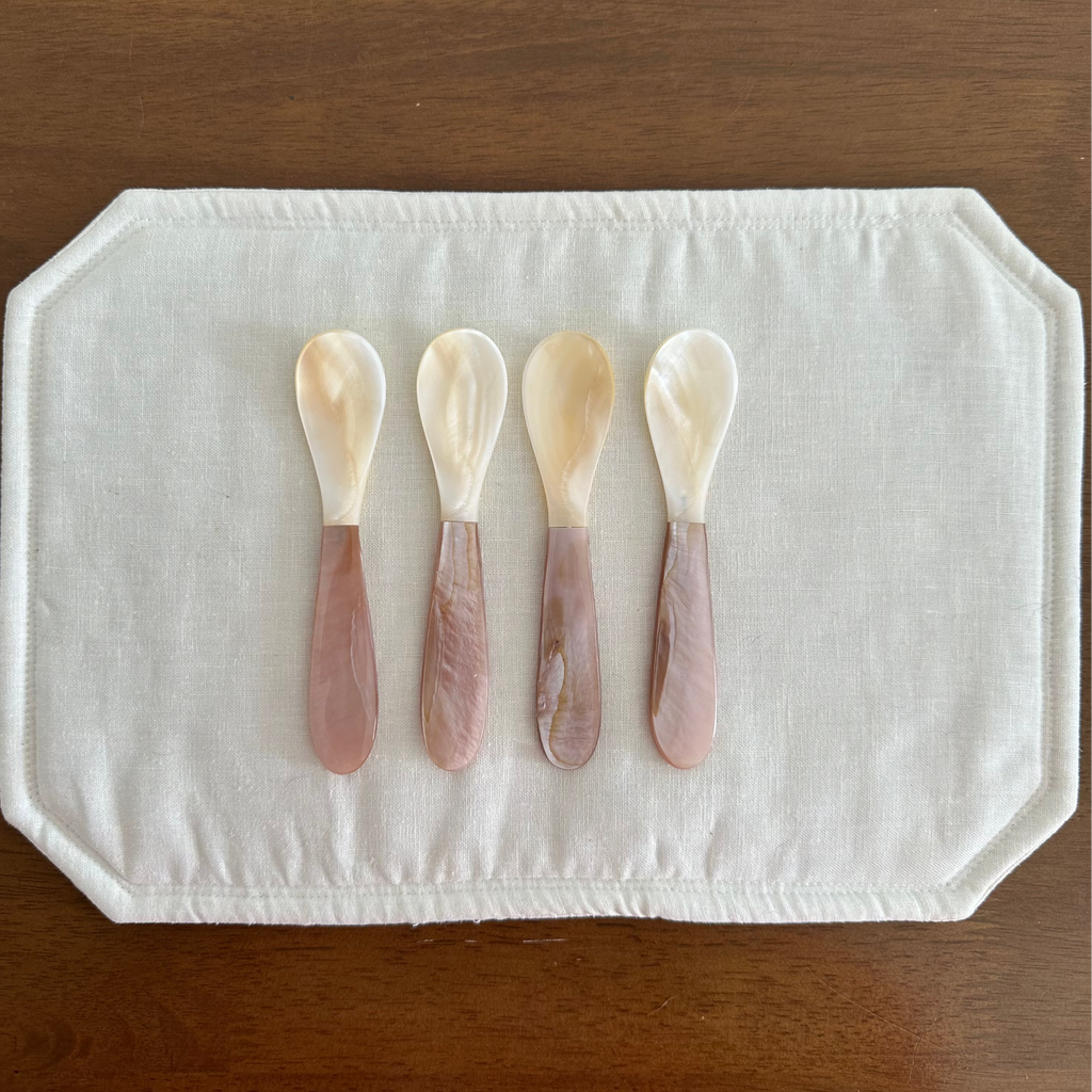 Mother of Pearl Spoon Pink and White on white placemat on wooden background