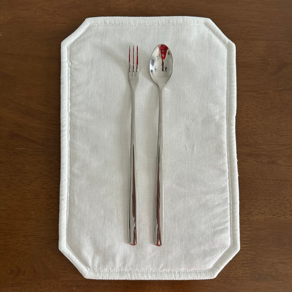 Fork and spoon on a white napkin with red stains on a wooden surface