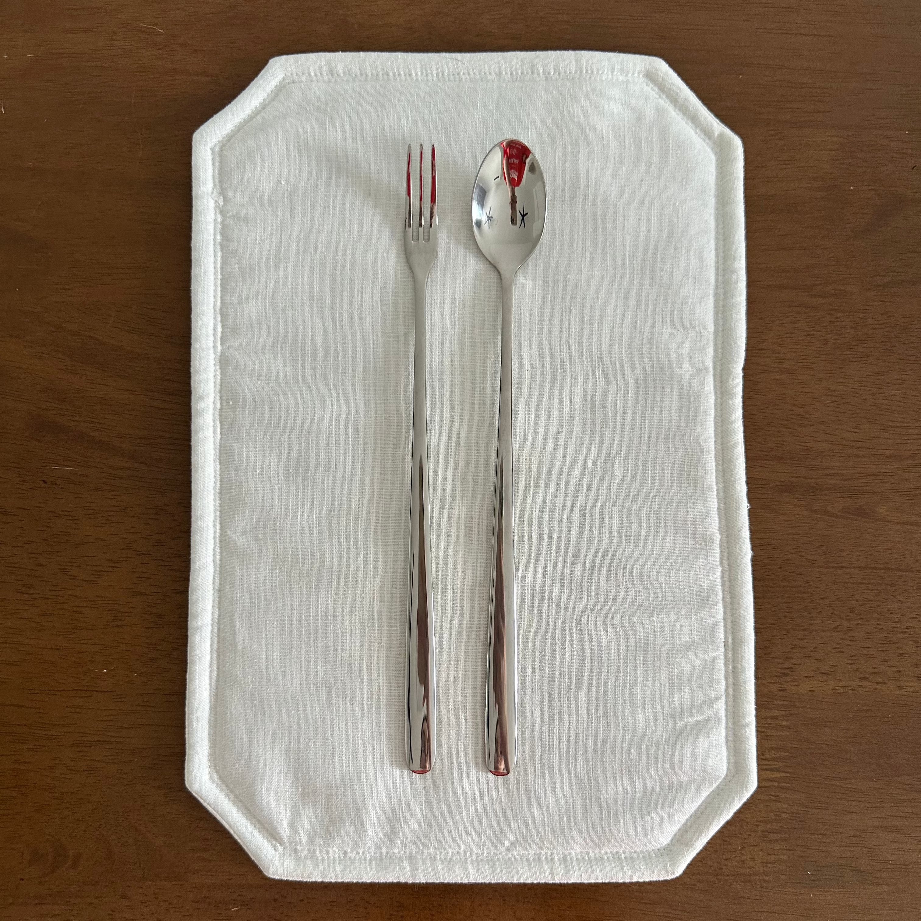 Fork and spoon on a white napkin with red stains on a wooden surface